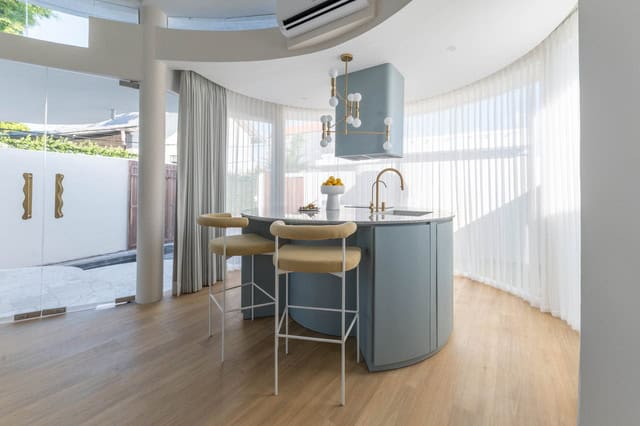 Modern kitchen with blue island and stools.