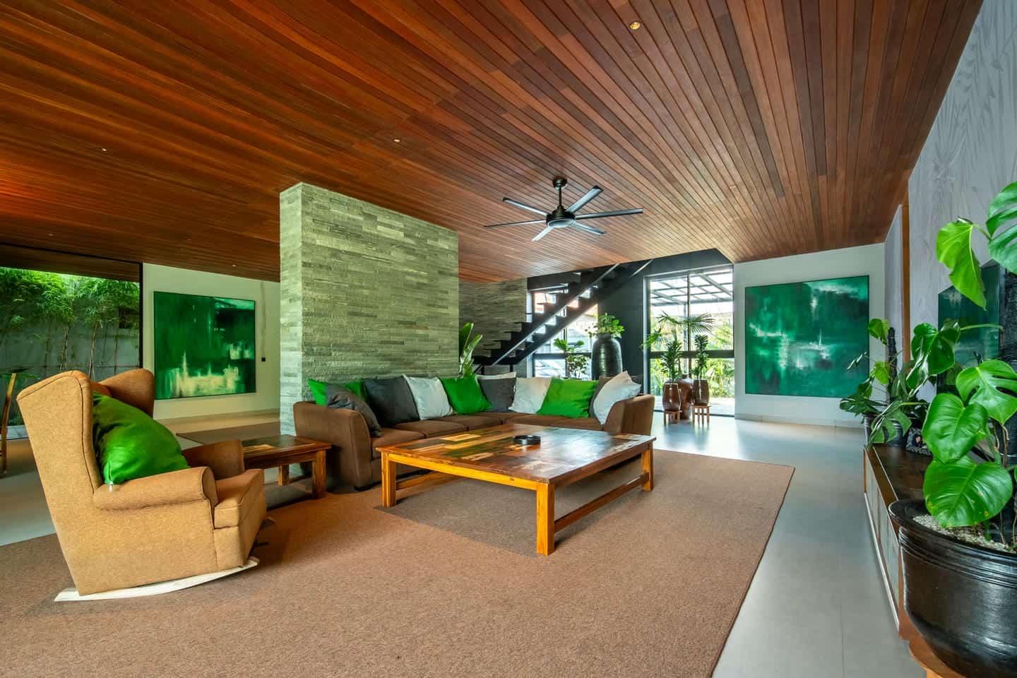 Modern living room with wooden ceiling and greenery.