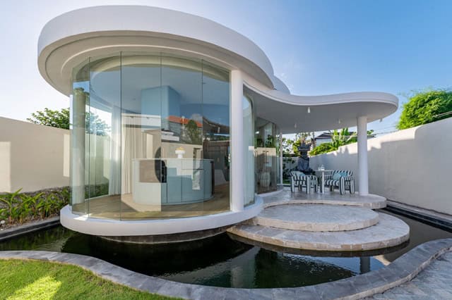 Modern glass-walled house with curved design and pond