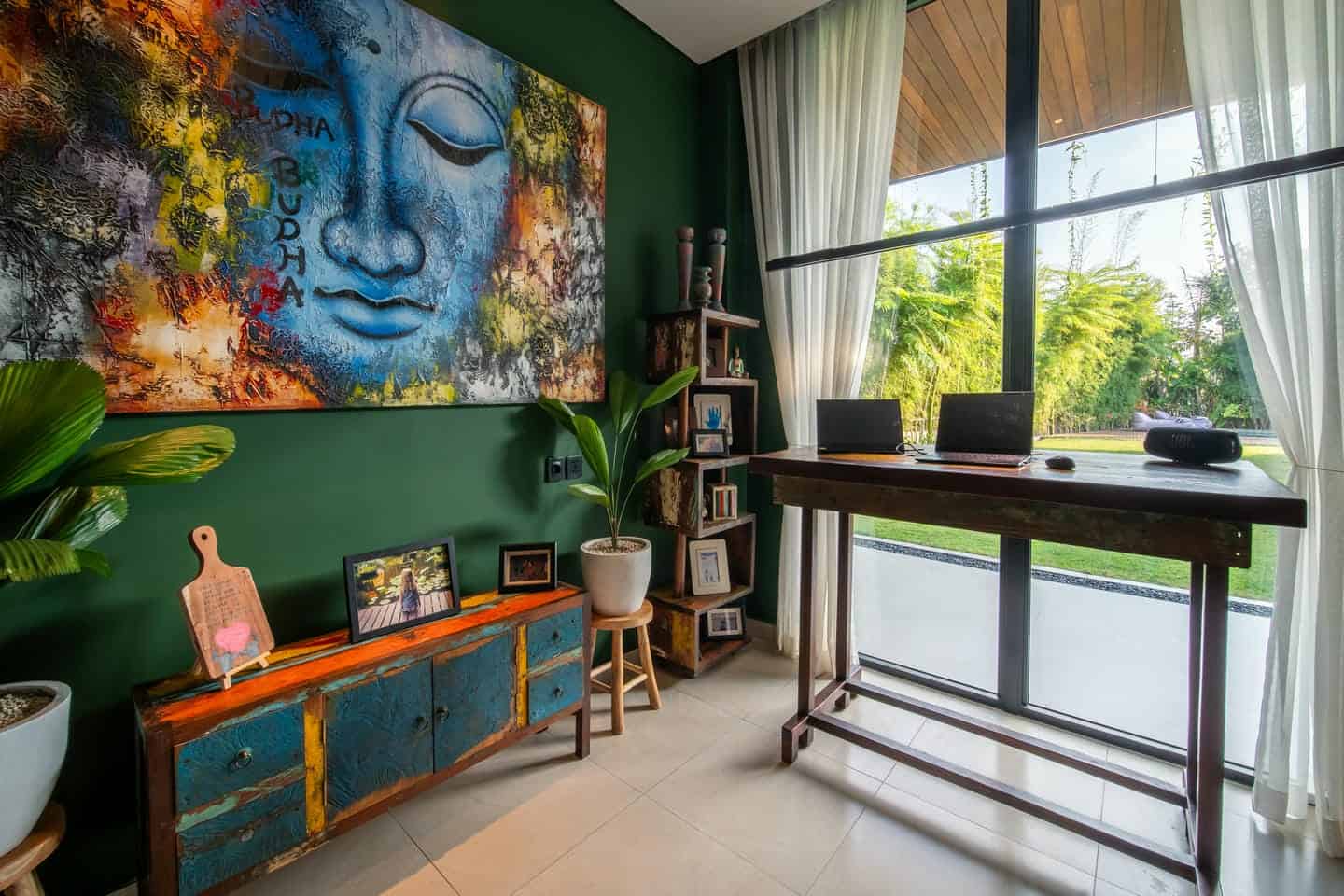 Stylish home office with Buddha painting and plants.