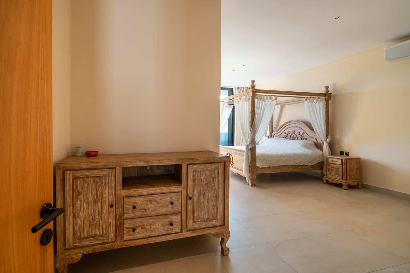 Spacious bedroom with wooden furniture and canopy bed.