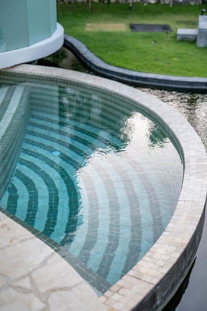 Elegant curved swimming pool with mosaic tiles.