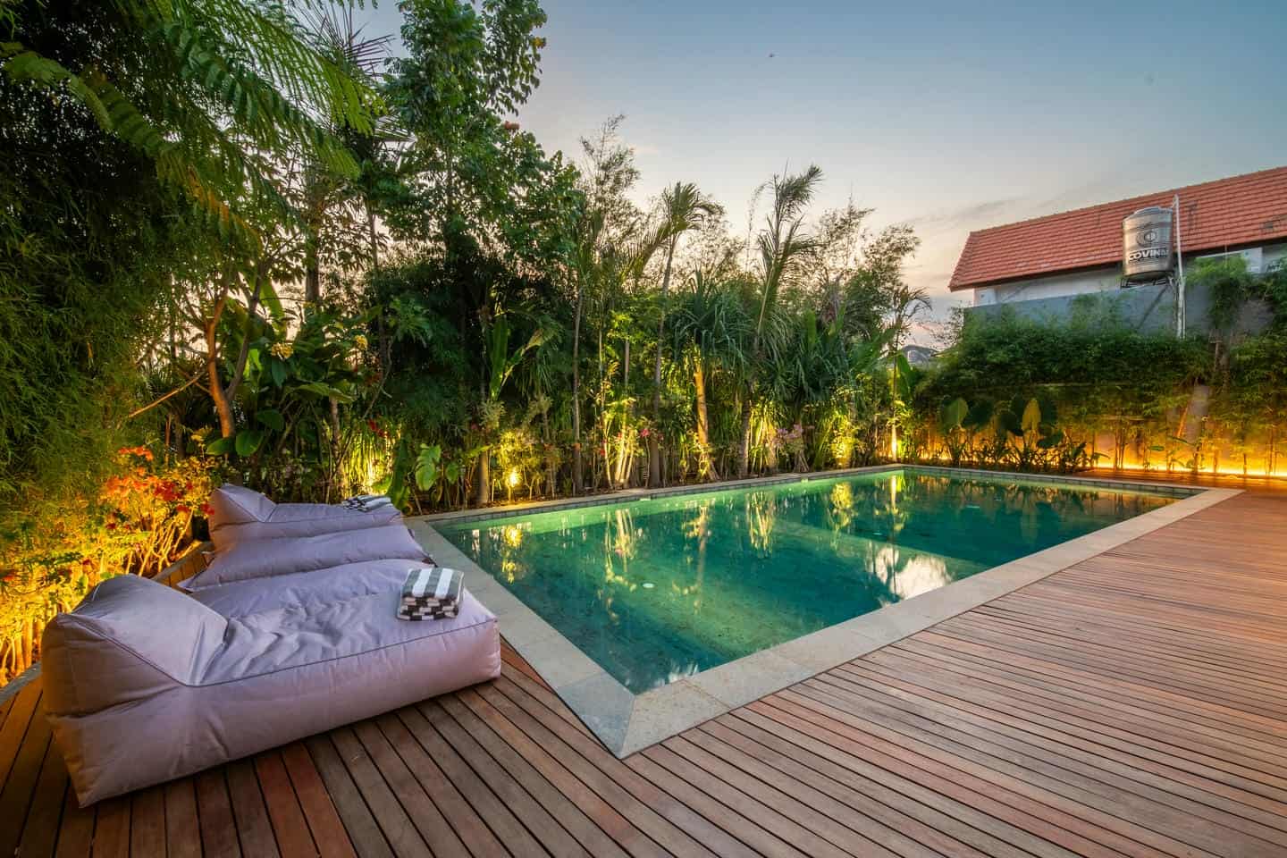 Tranquil outdoor pool with lush greenery at sunset.