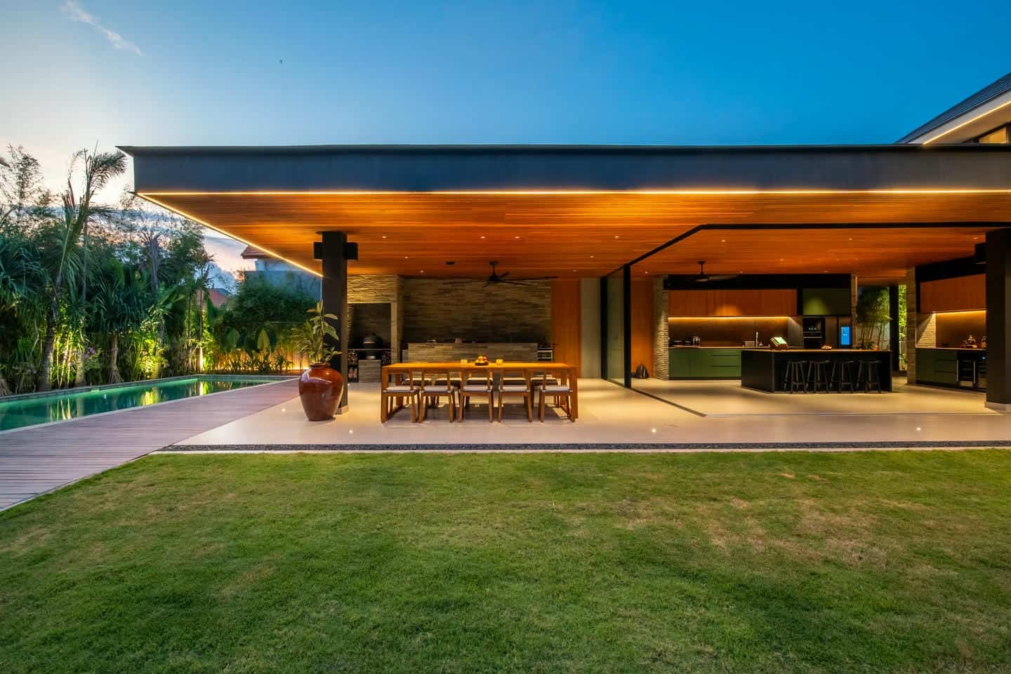 Modern outdoor kitchen near a pool at sunset.