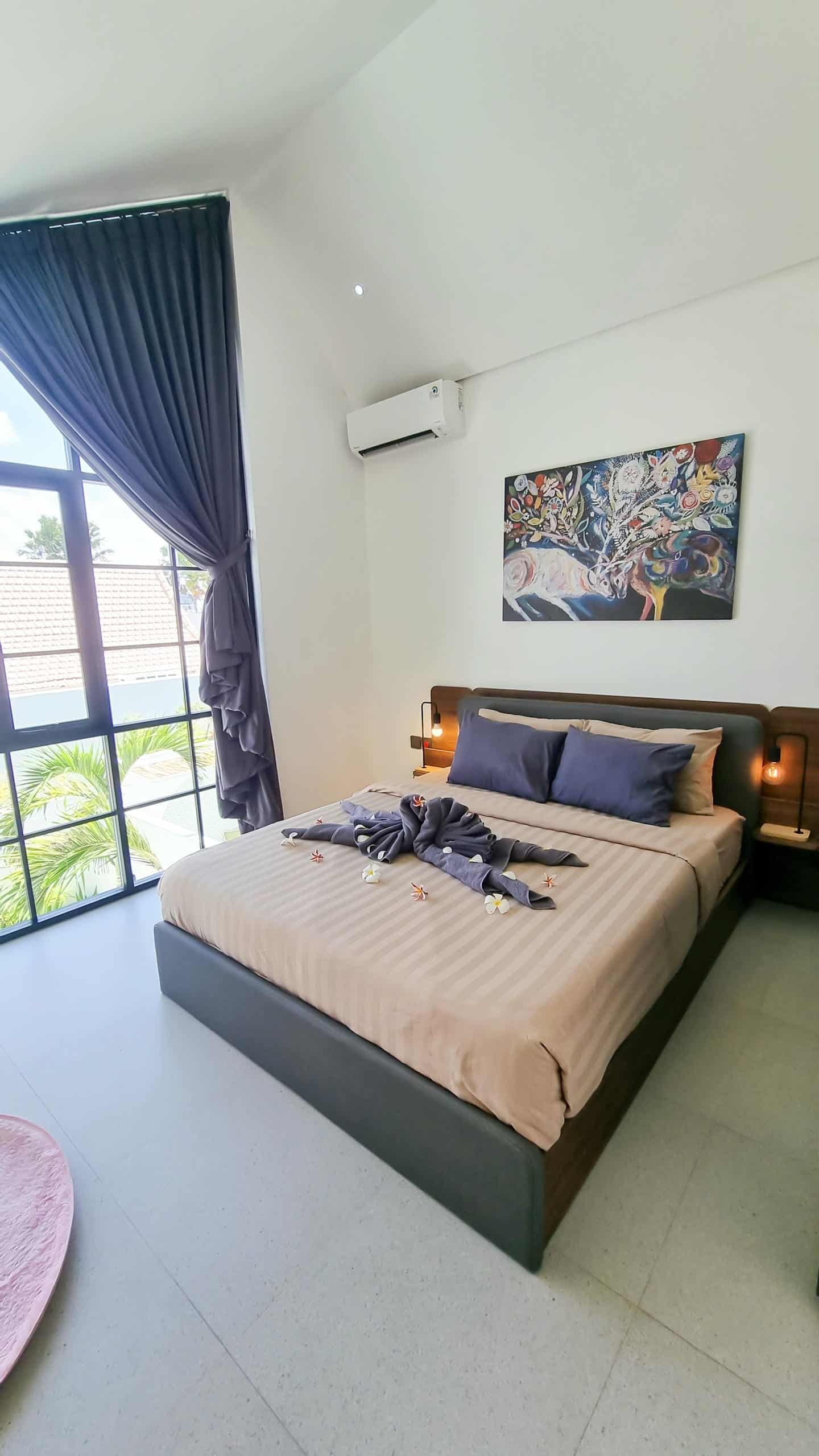 Modern bedroom with large window and decorative bed.