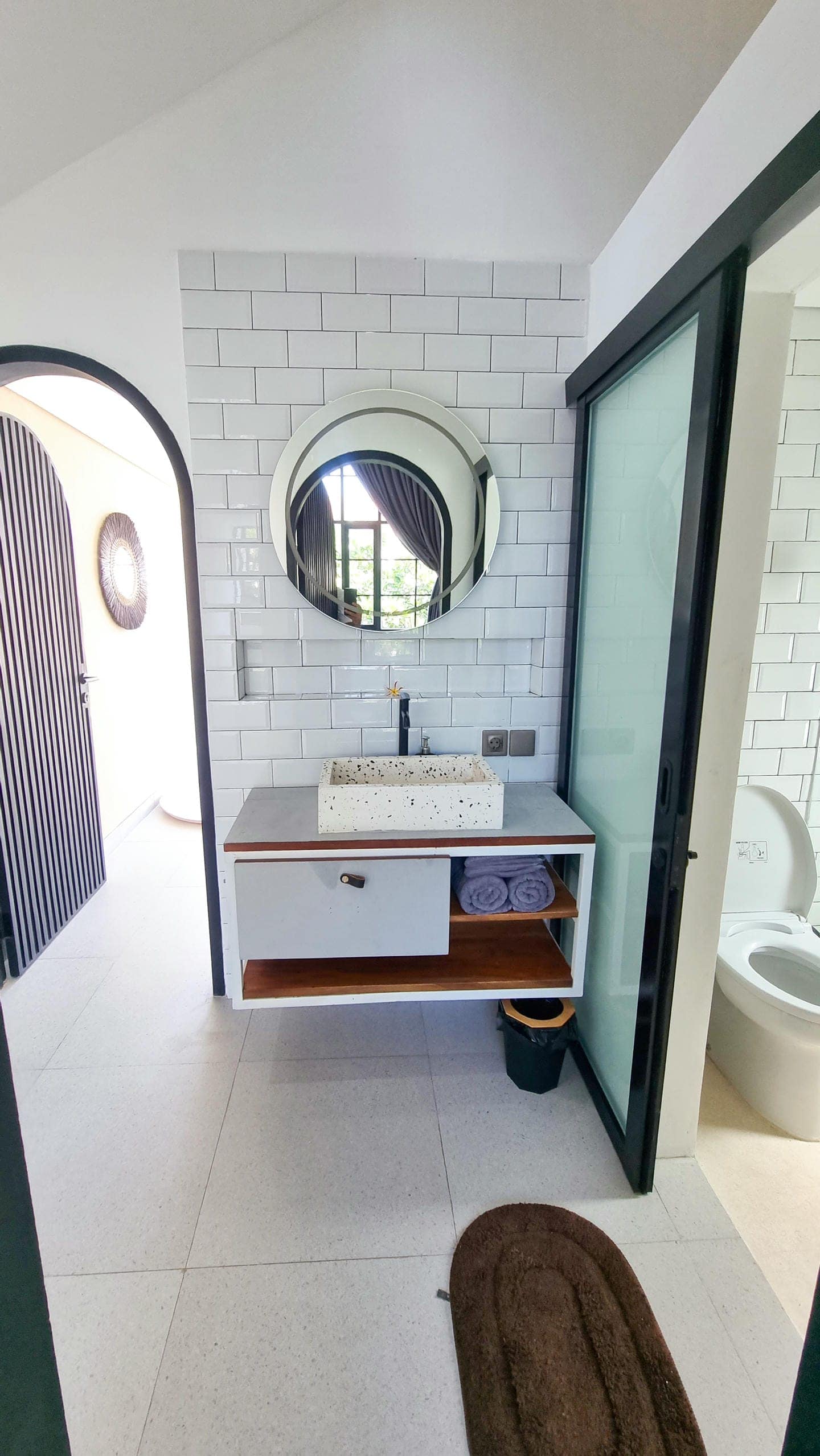 Modern bathroom with round mirror and vessel sink.