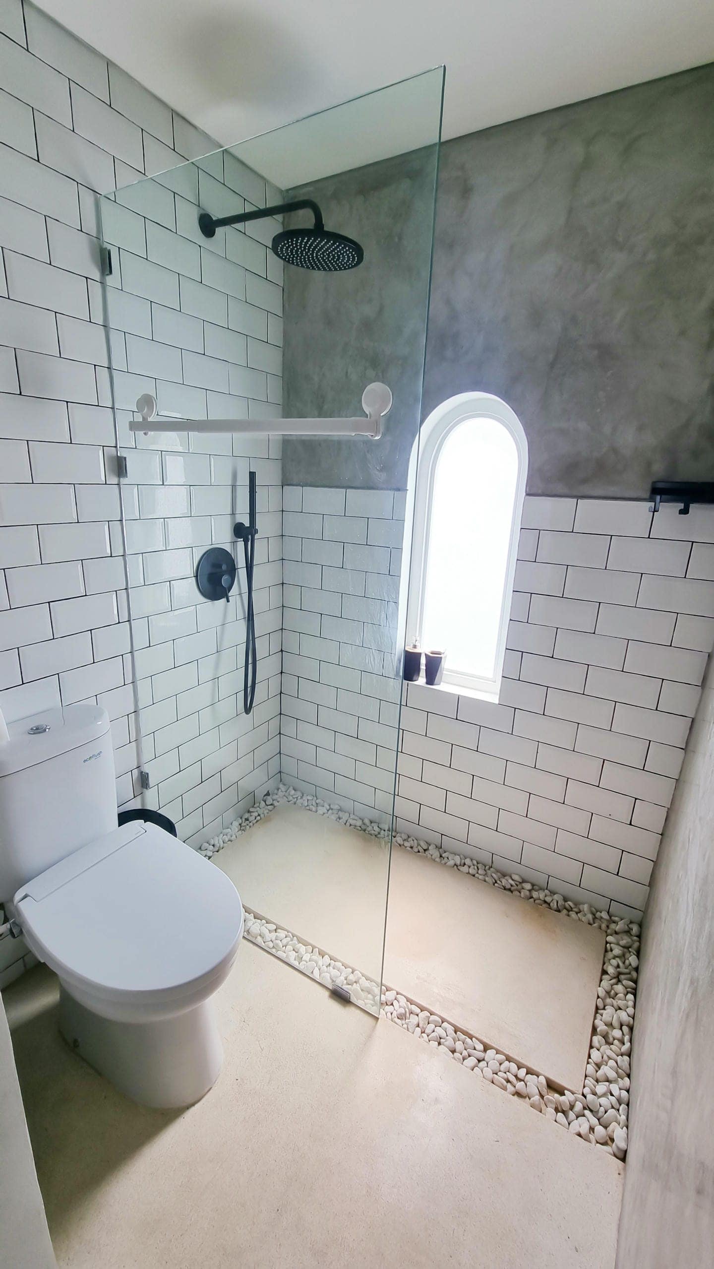 Modern bathroom with glass shower and white tiles.