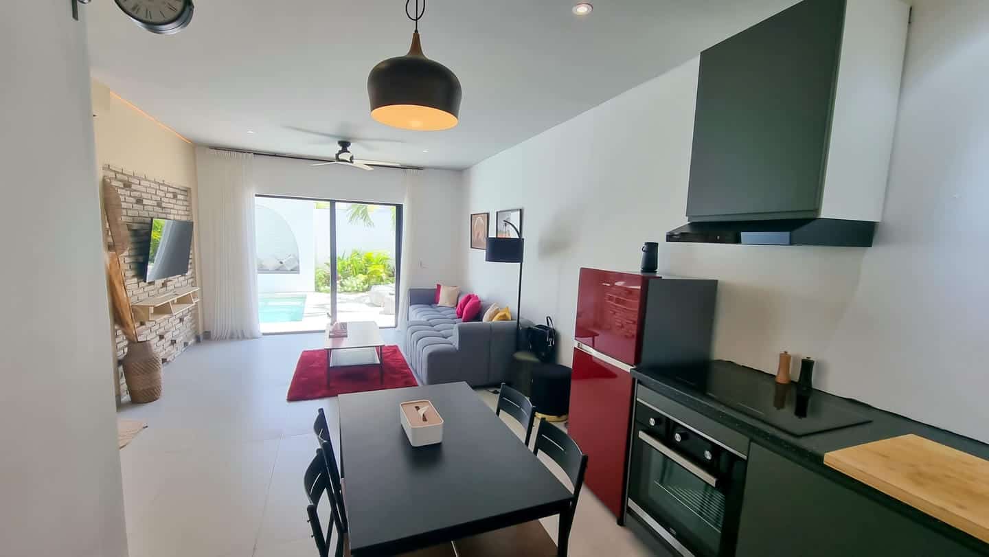 Modern living room with kitchen and pool view.