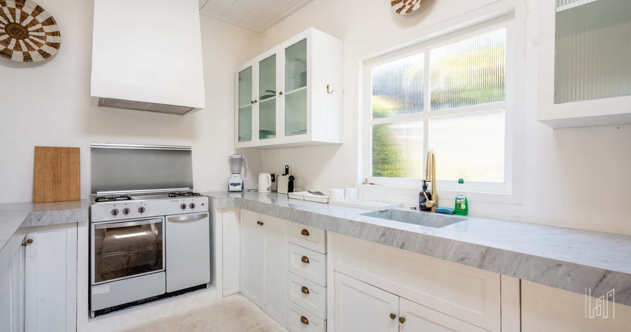 Modern white kitchen with marble countertops.