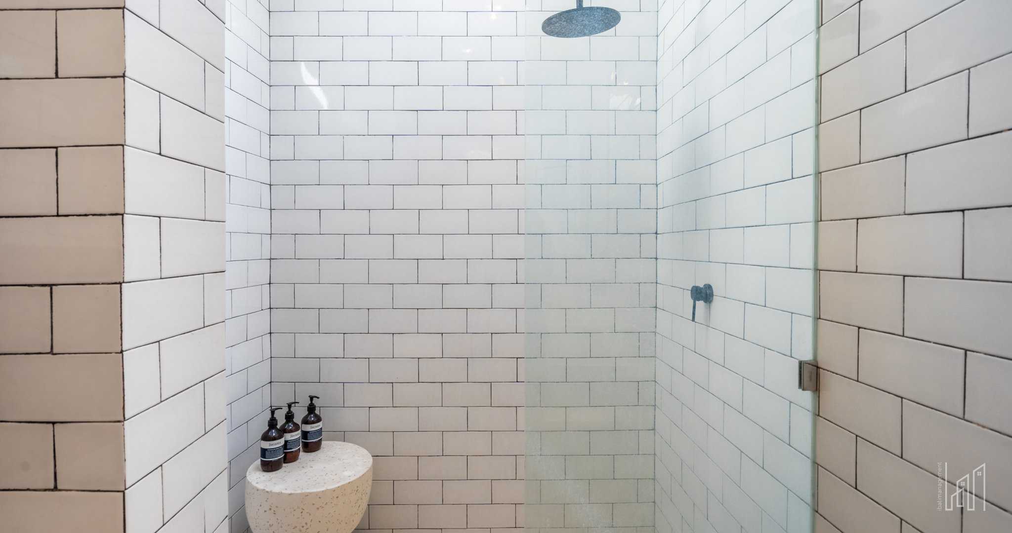 Modern tiled shower with glass door and toiletries