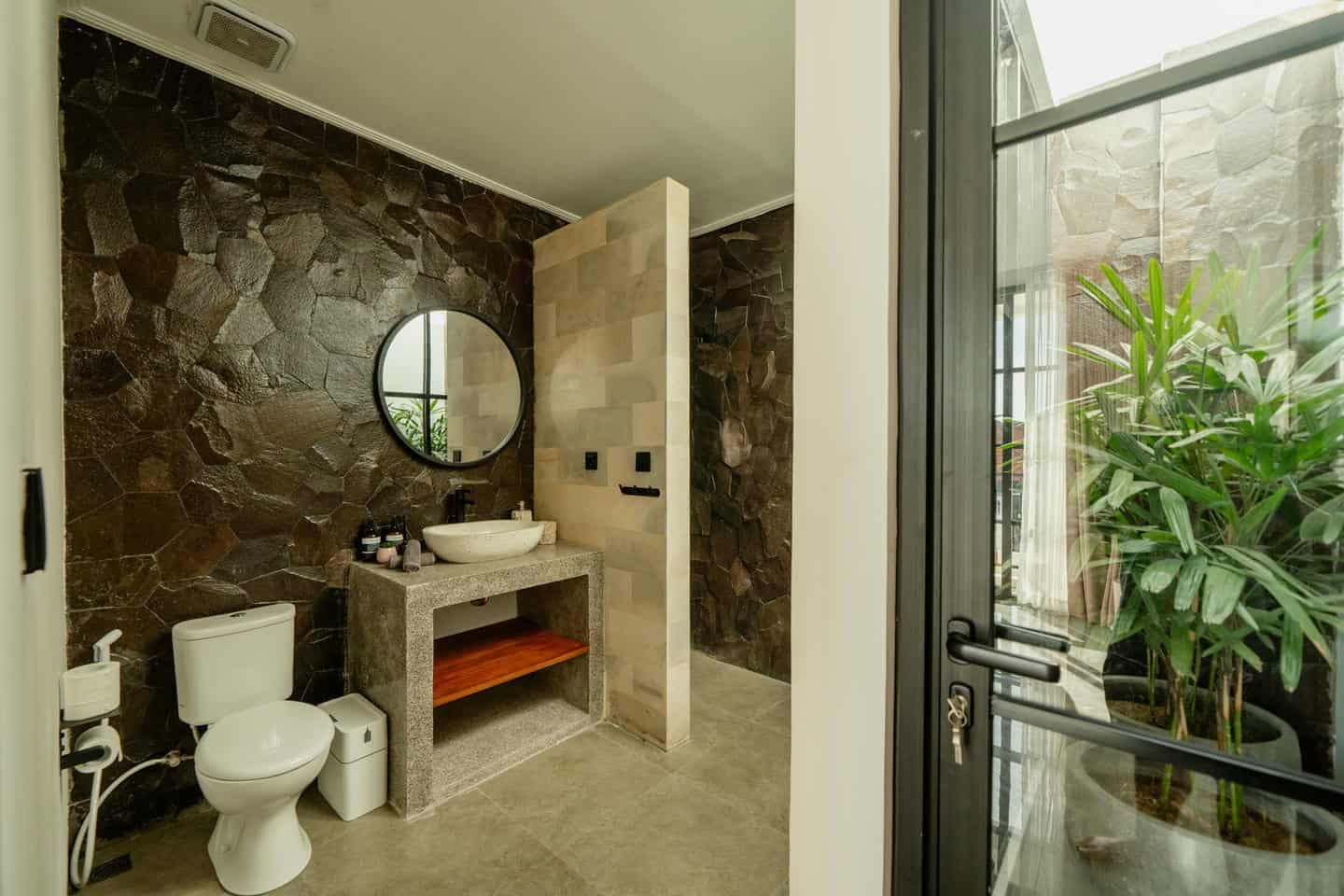 Modern bathroom with stone walls and glass door.