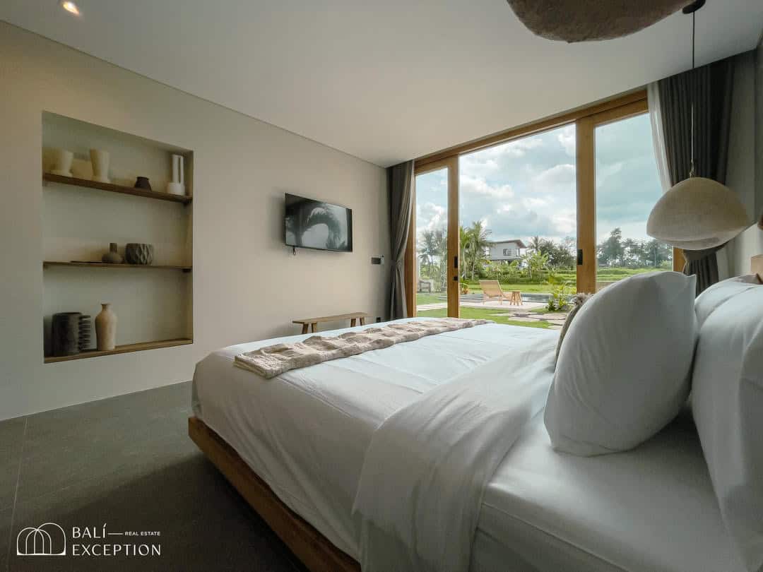 Modern bedroom with garden view through large windows.