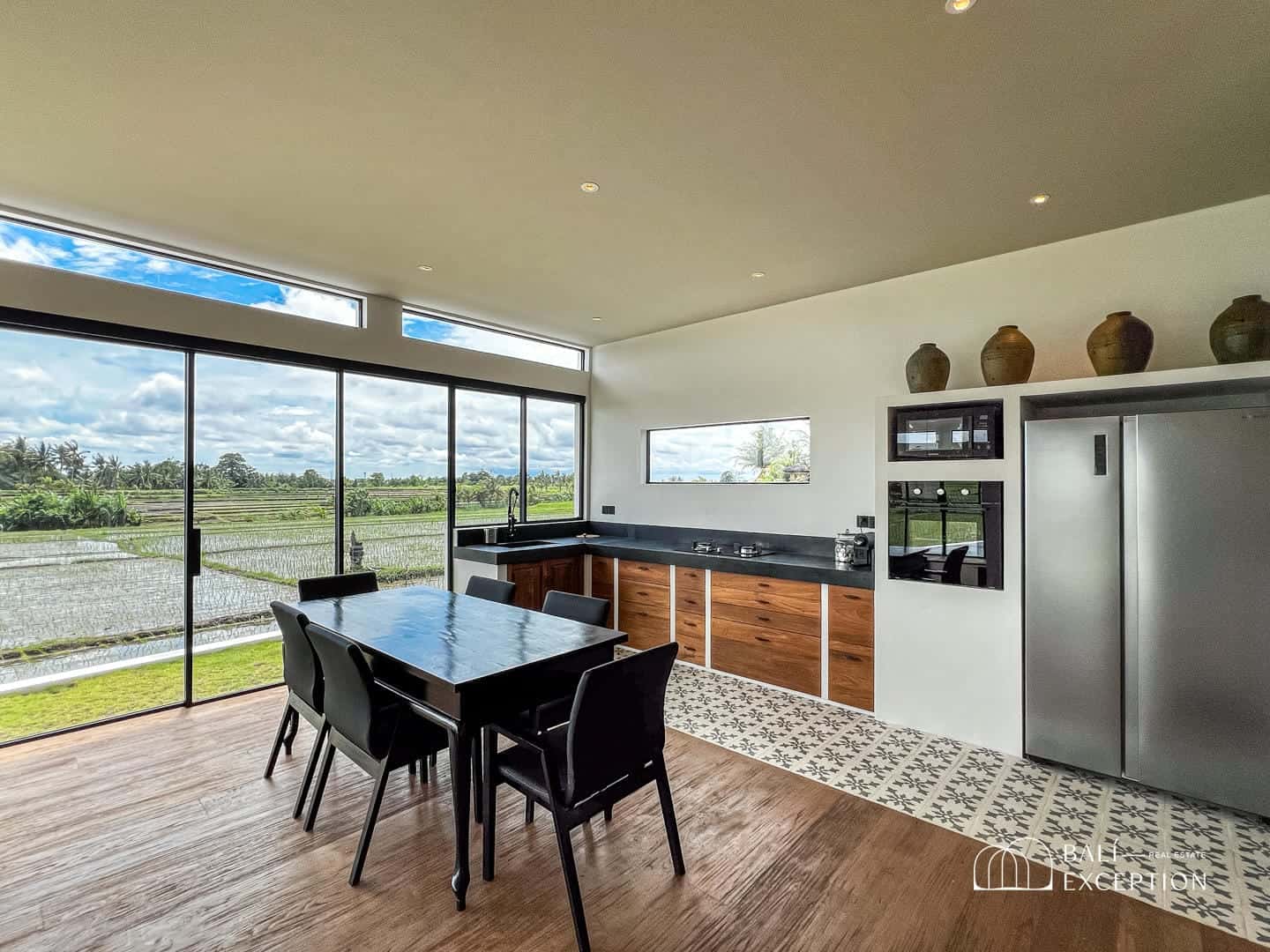 Modern kitchen with large windows overlooking fields.
