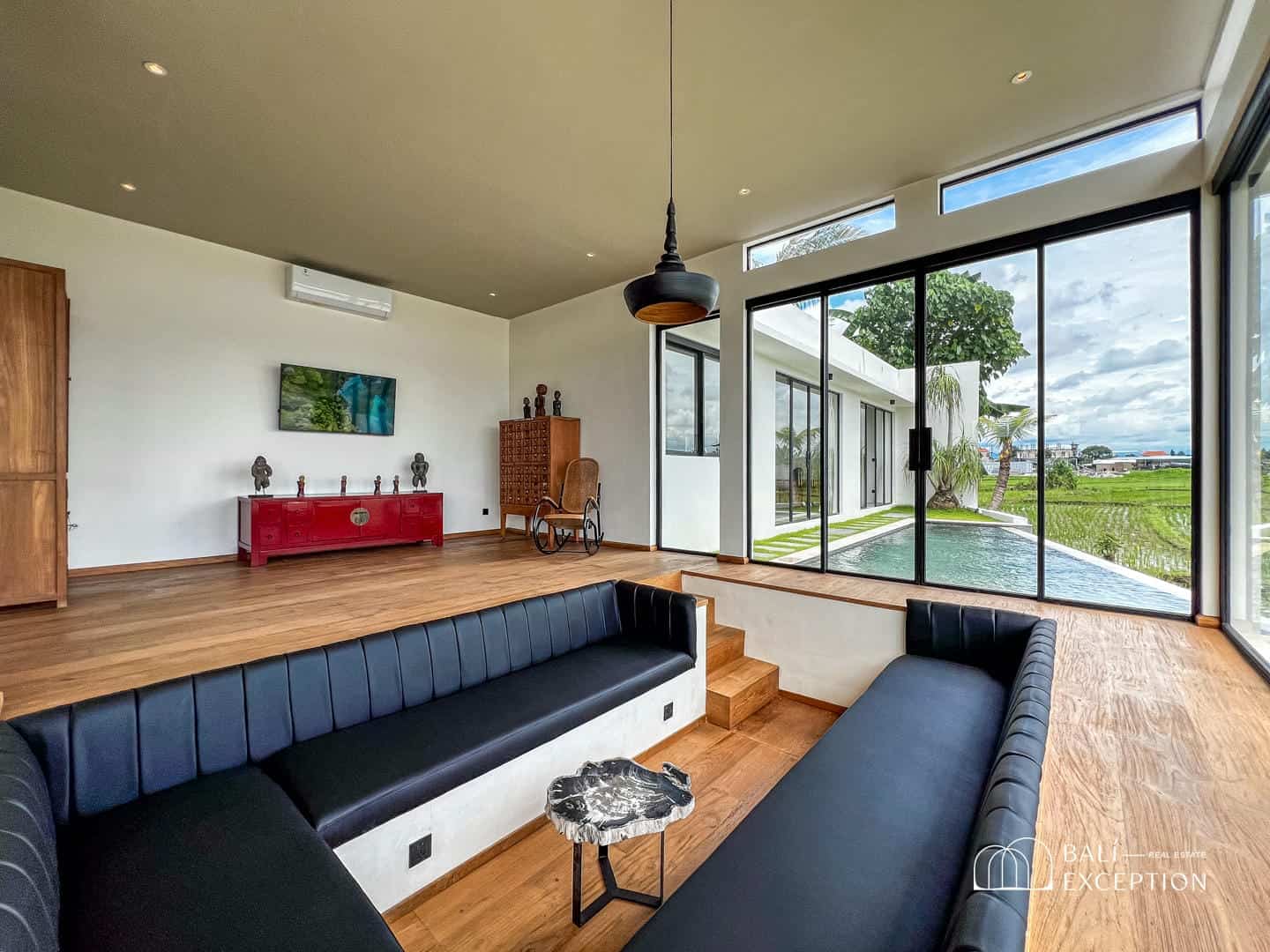 Modern living room with pool view and red cabinet.
