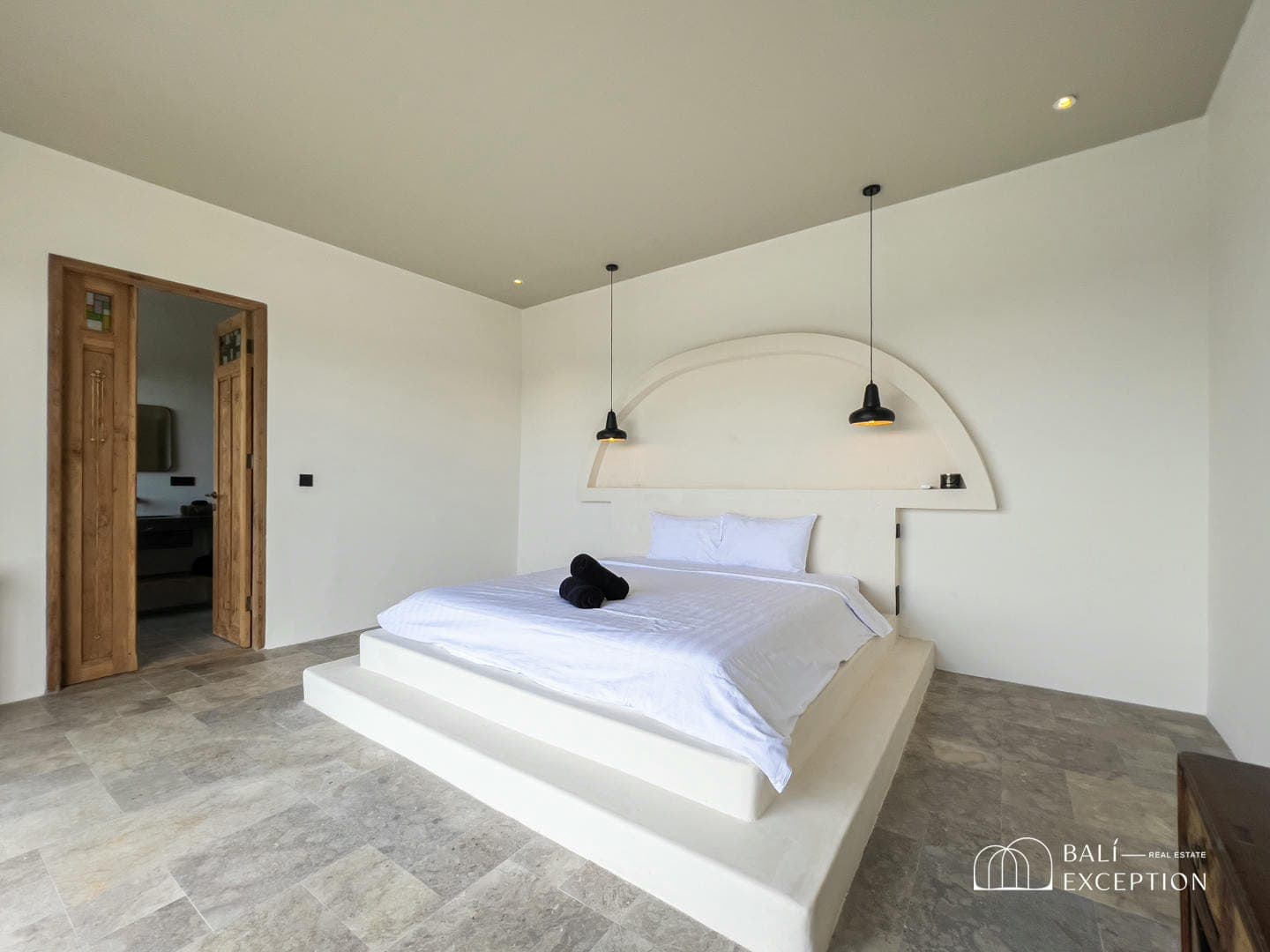 Minimalist bedroom with white bed and pendant lights.