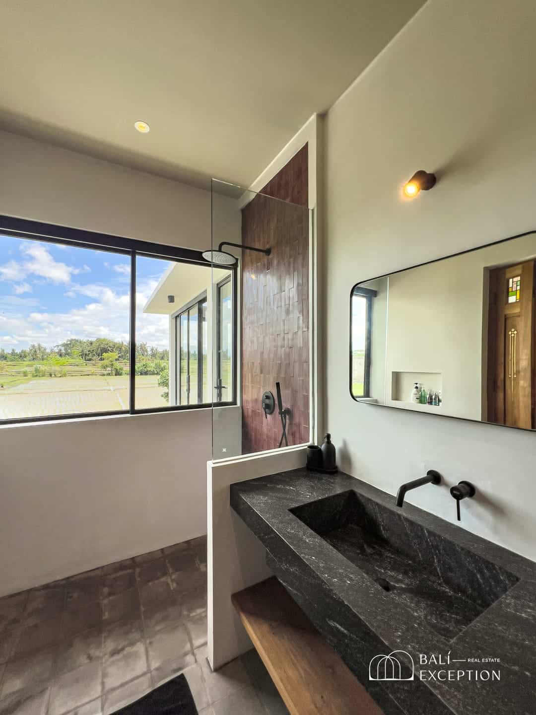 Modern bathroom with black stone sink and large window.