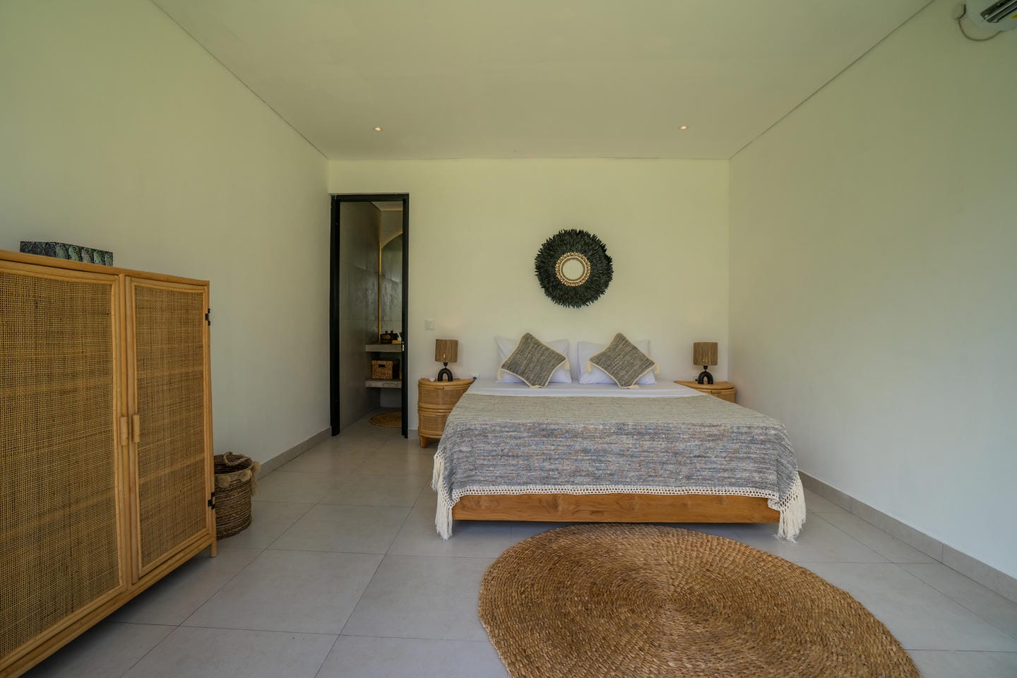 Modern bedroom with wicker furniture and decorative mirror.