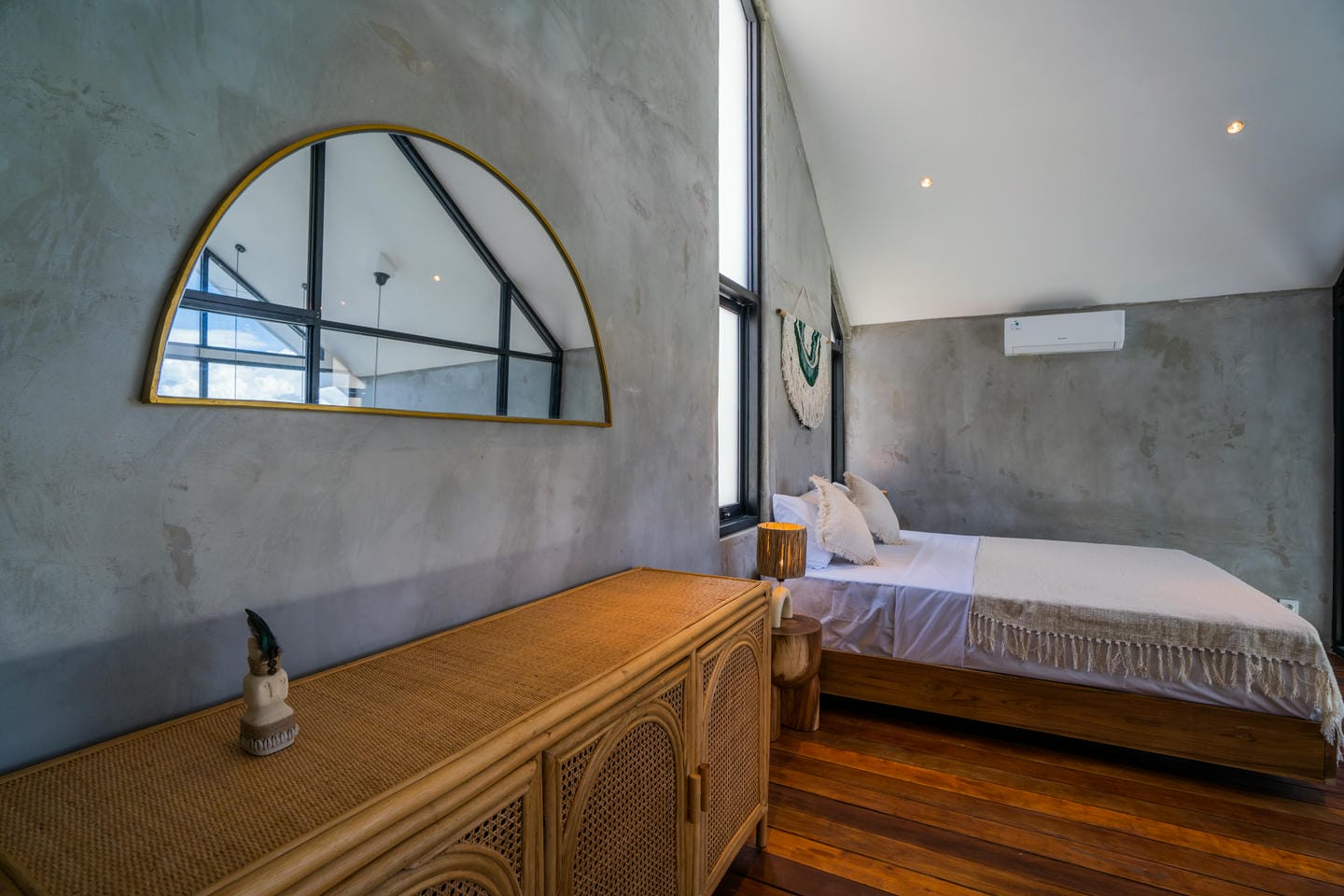 Modern minimalist bedroom with wooden floors and large mirror.
