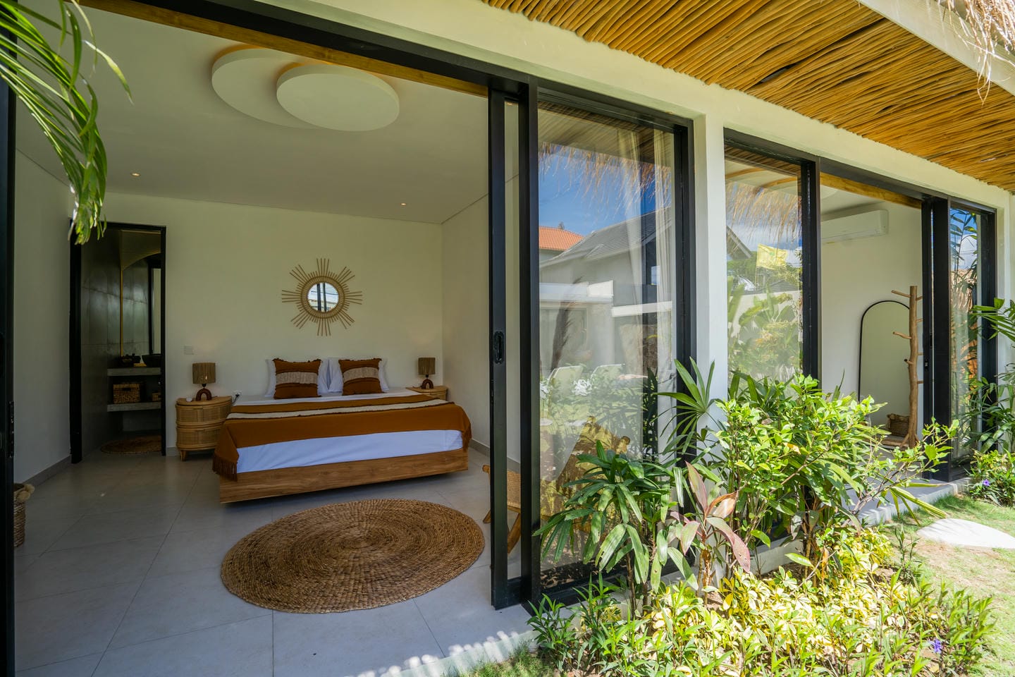 Modern bedroom with glass doors and outdoor garden view.