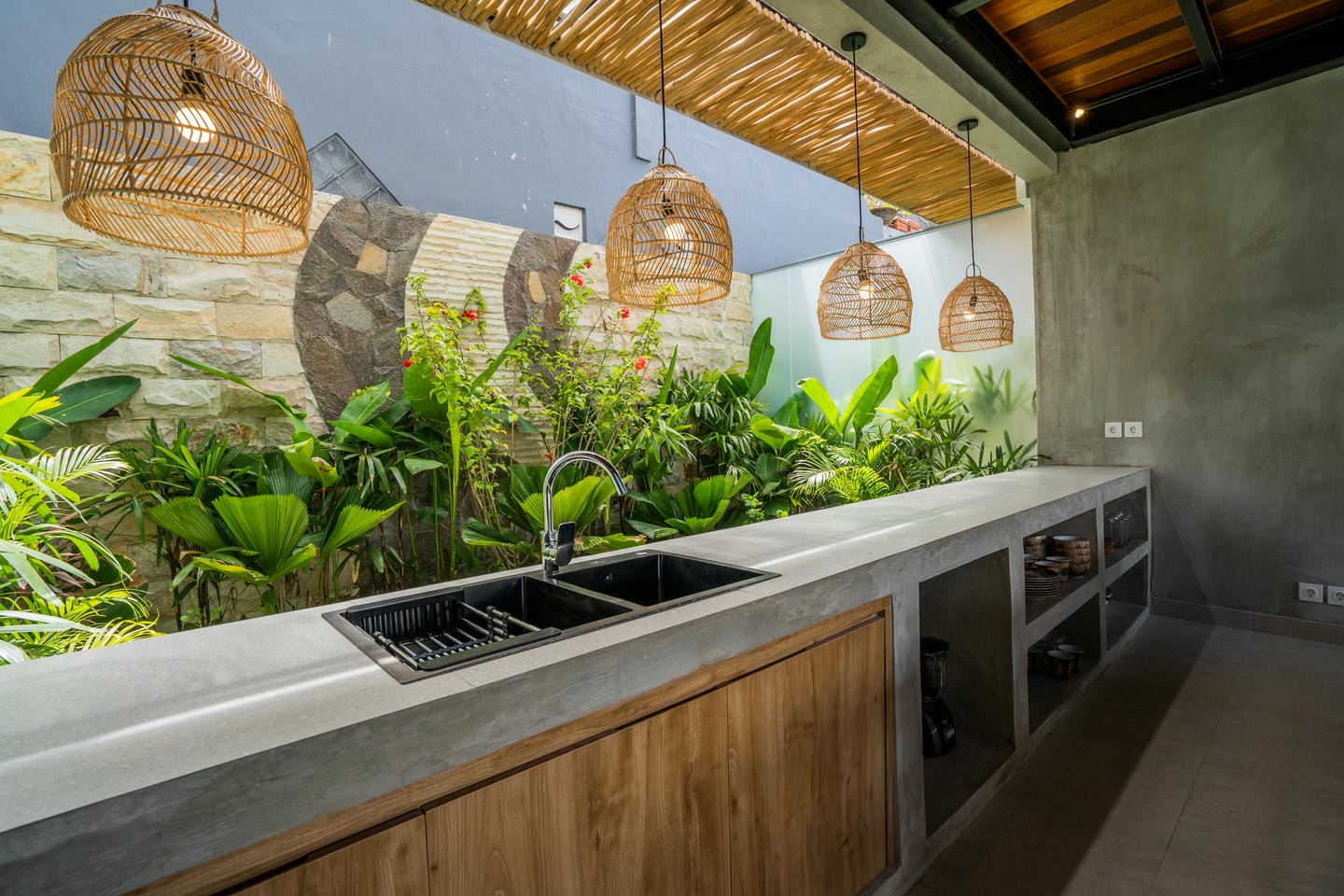 Outdoor kitchen with hanging lights and plants.