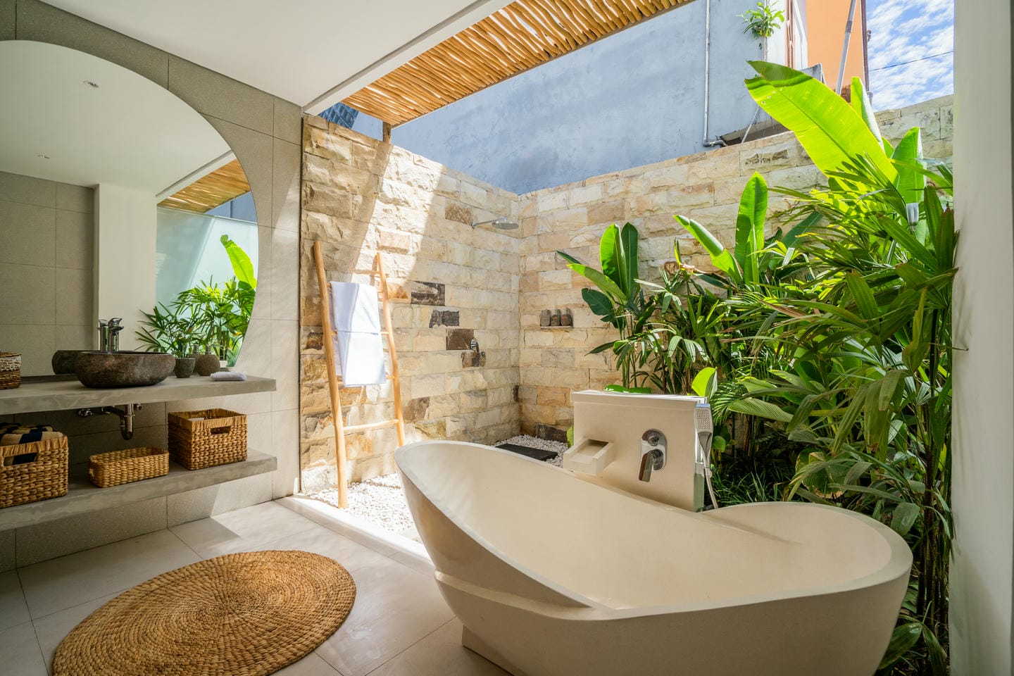 Luxurious outdoor bathroom with bathtub and plants.