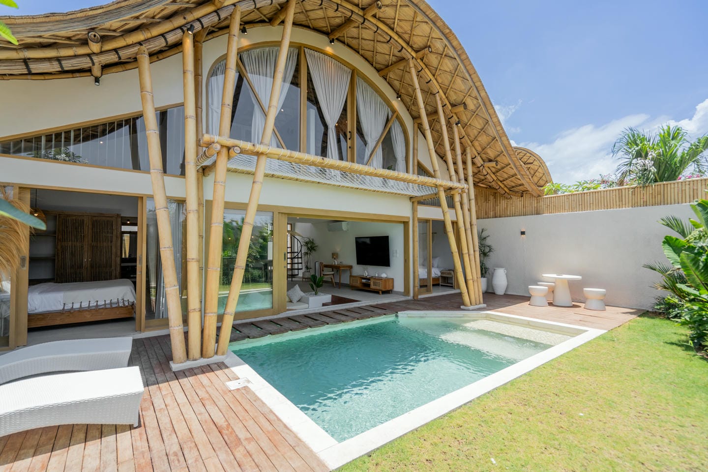 Modern bamboo villa with pool and patio furniture.