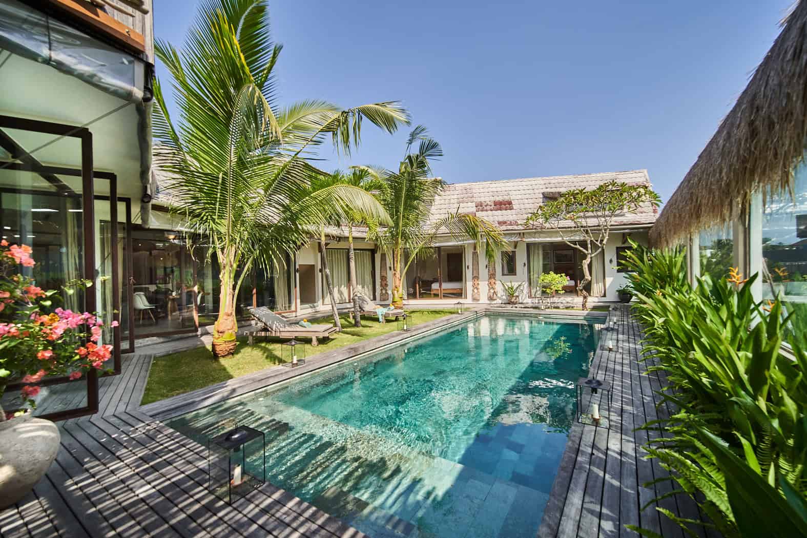 Tropical villa courtyard with pool and palm trees.
