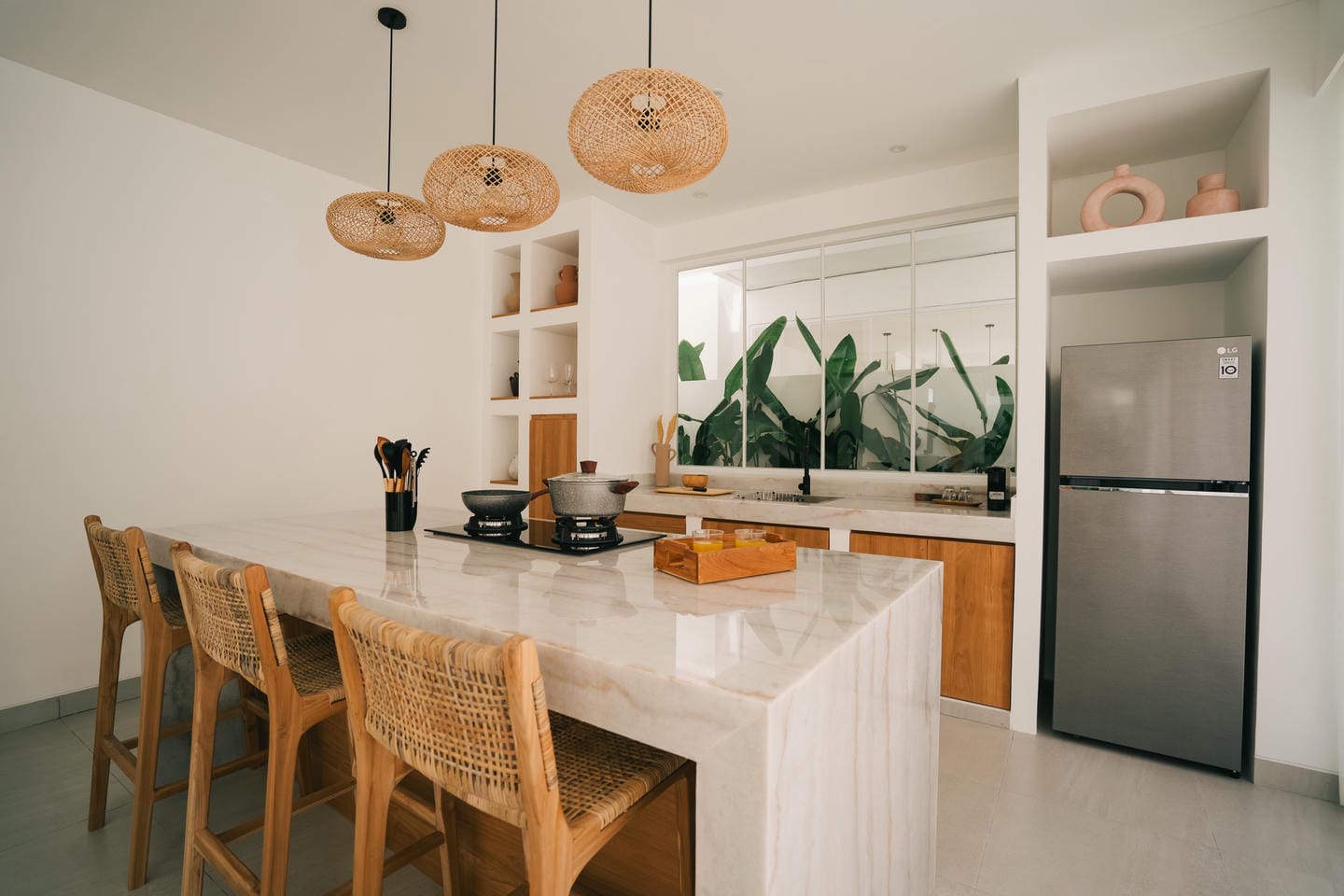 Modern kitchen with island, plants, and wicker lights.