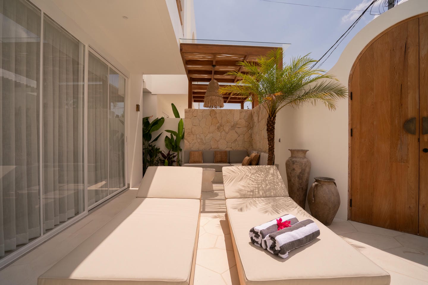 Outdoor patio with loungers and potted plants.