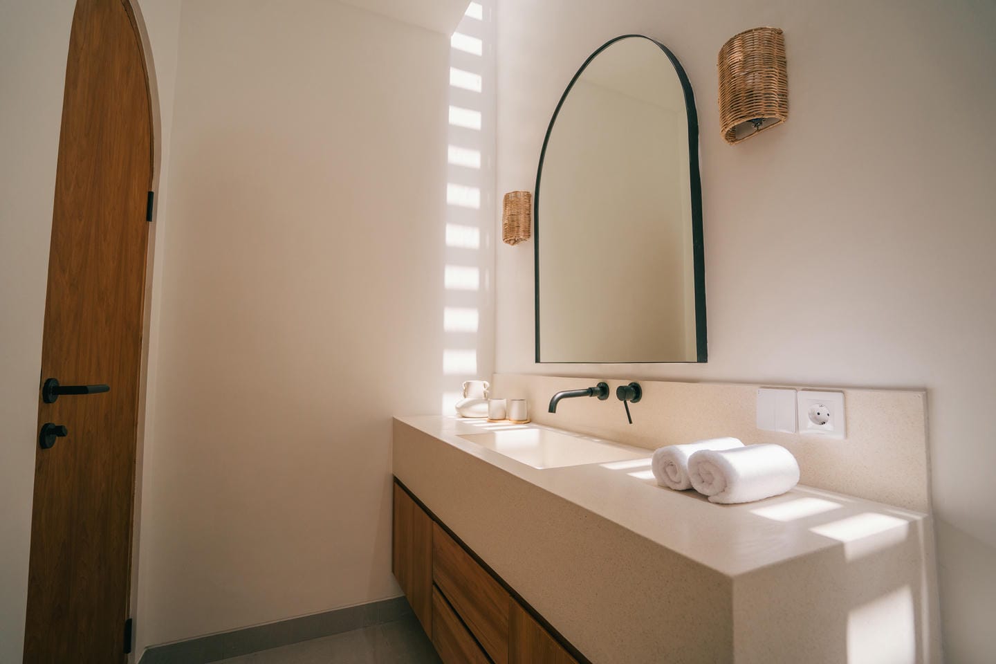Minimalist bathroom with large mirror and natural light.
