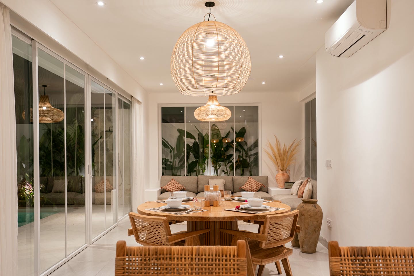 Modern dining room with wicker decor and large windows.