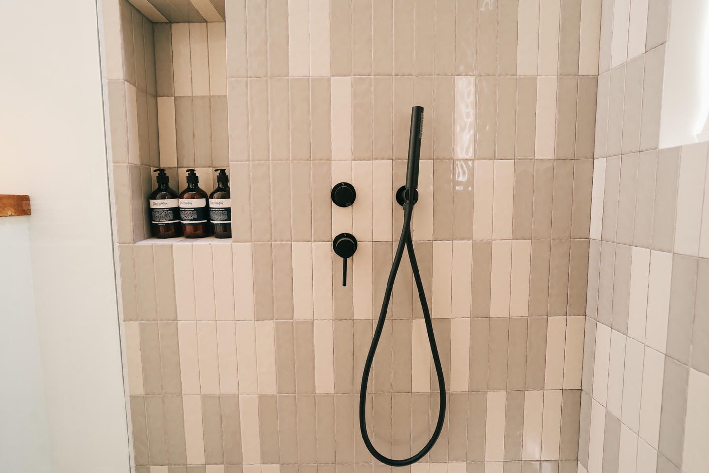 Shower with beige tiles and soap bottles