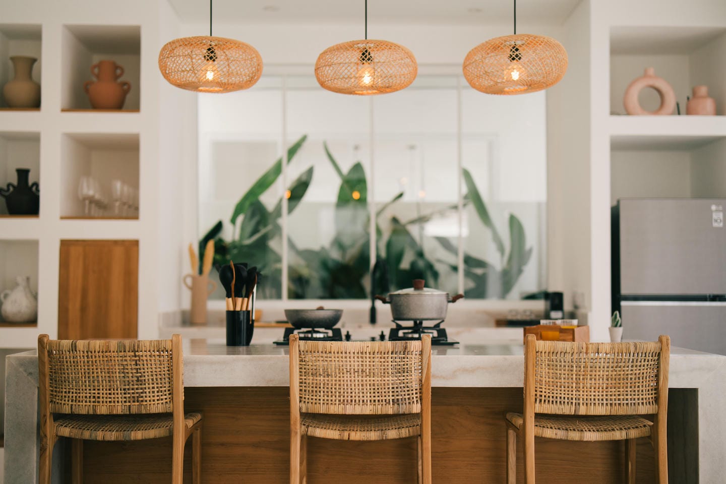 Modern kitchen with rattan lamps and island seating.