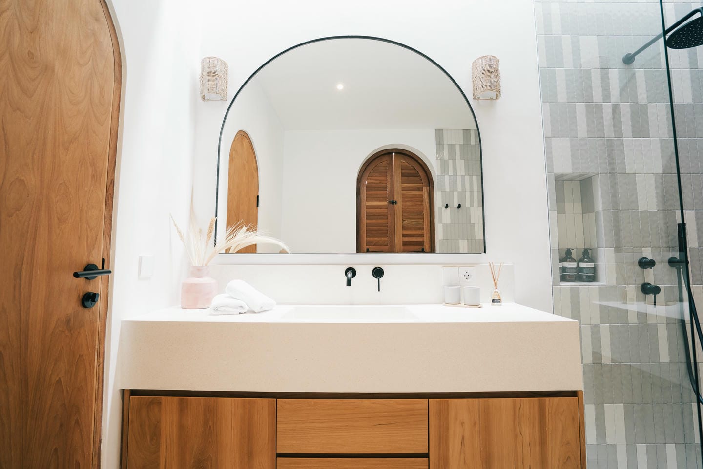 Modern bathroom with wooden door and large mirror.