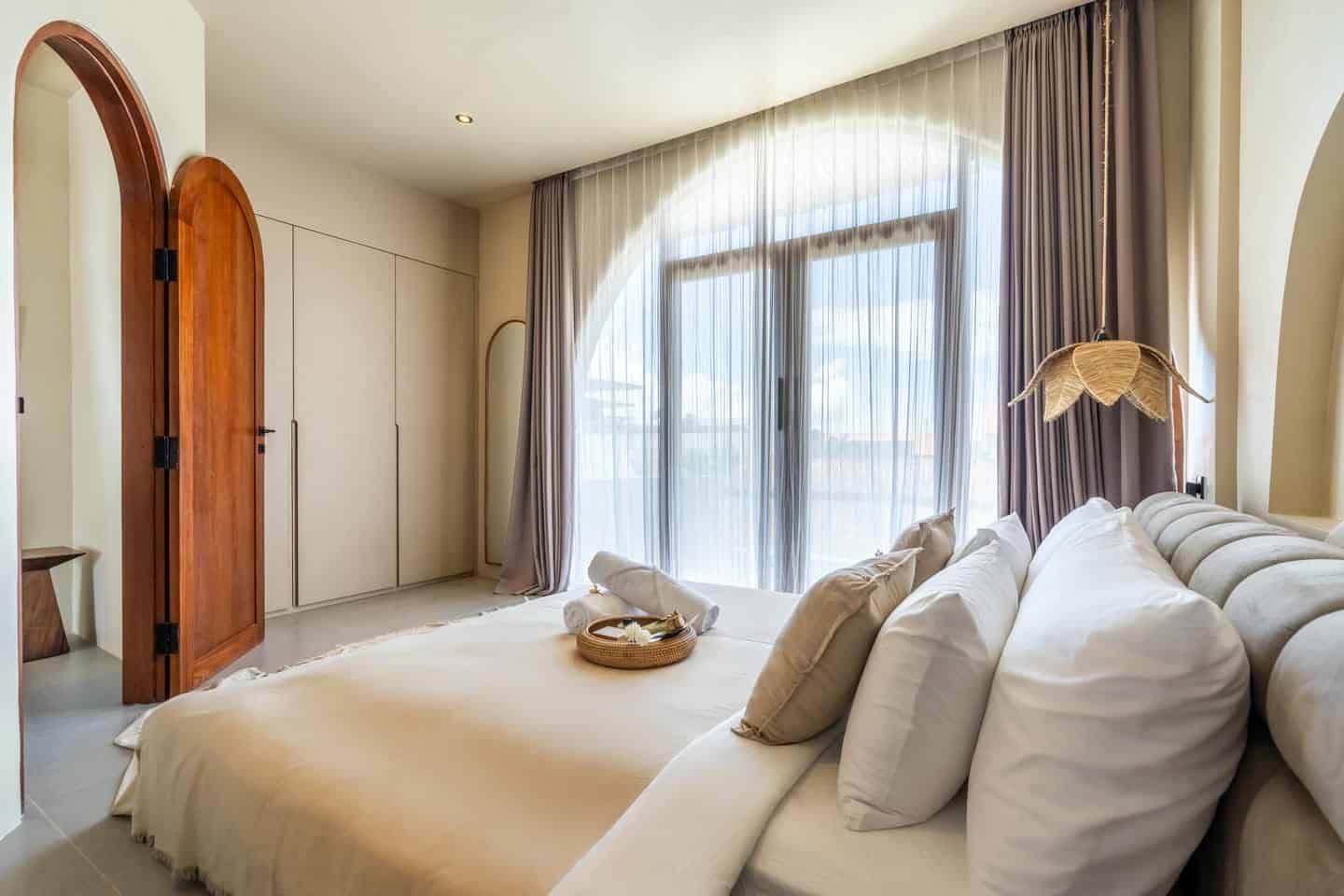 Luxurious bedroom with large window and cozy bed.