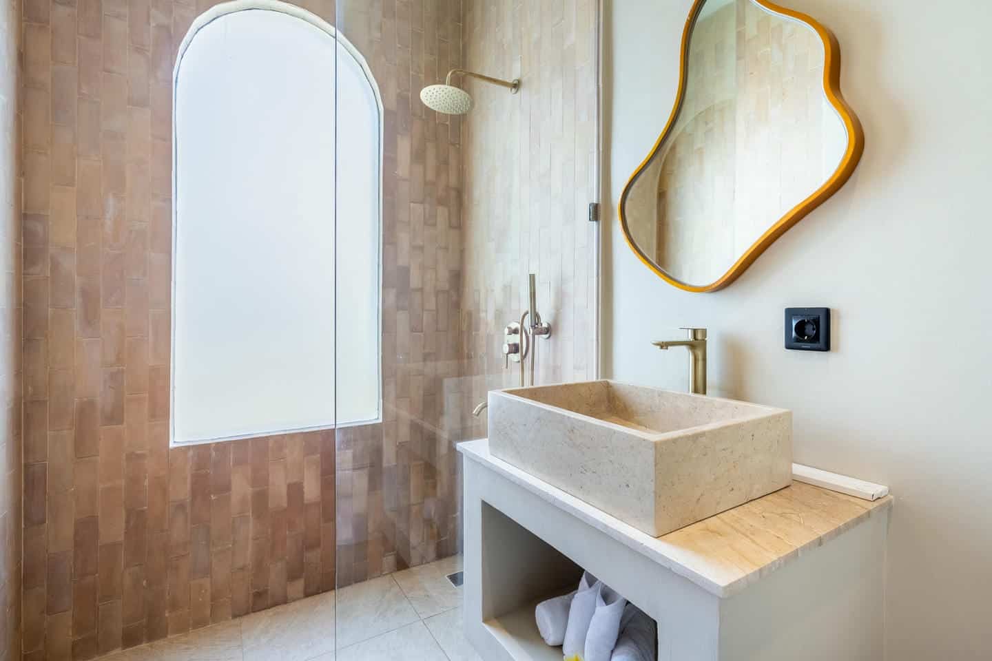 Modern bathroom with stone sink and unique mirror.