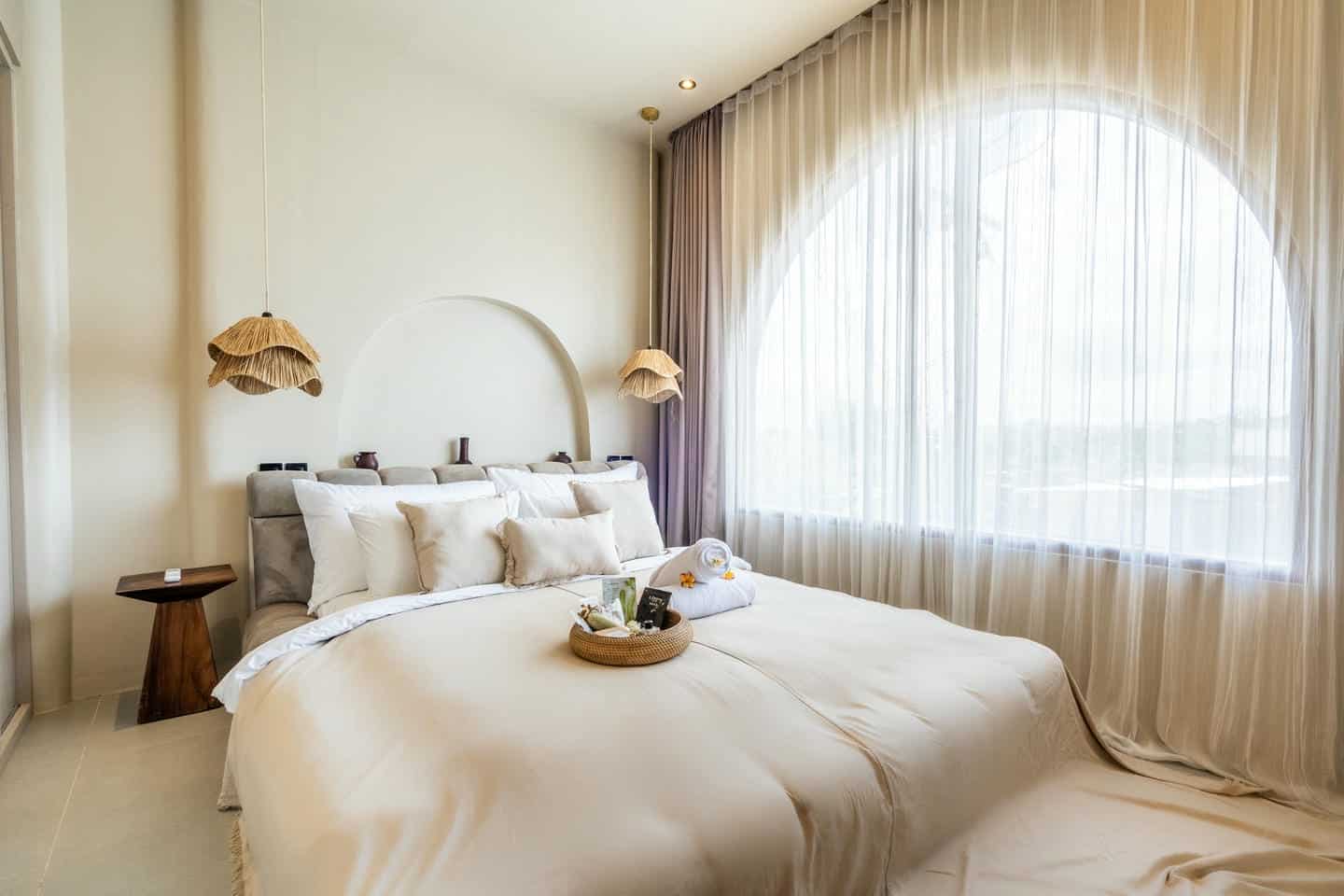 Minimalist bedroom with large windows and neutral decor.
