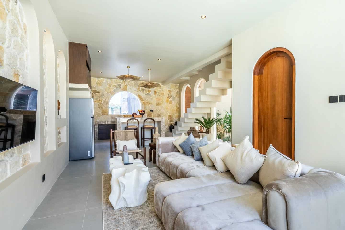 Modern living room with stone walls and staircase.