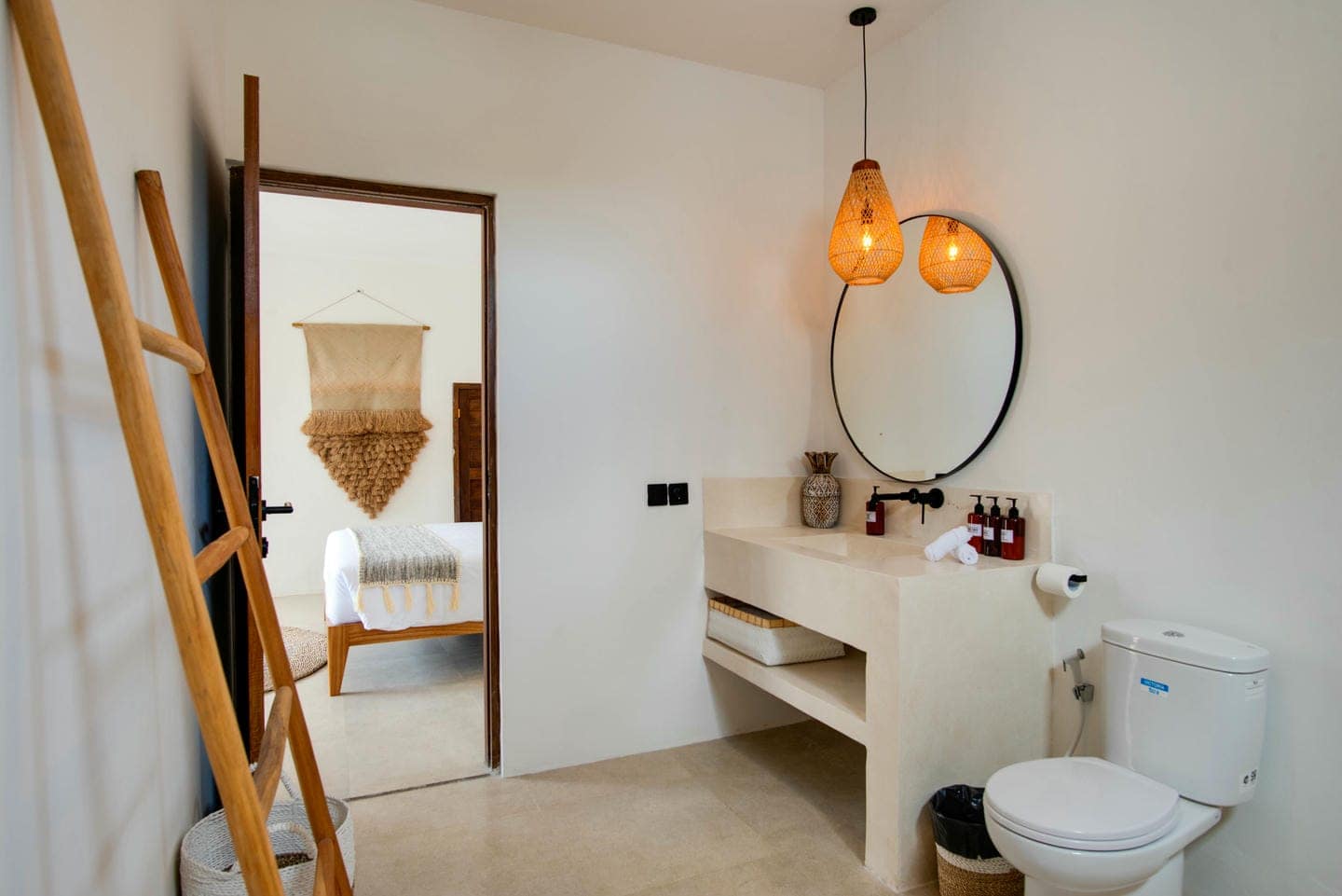 Modern bathroom with round mirror and pendant lights.