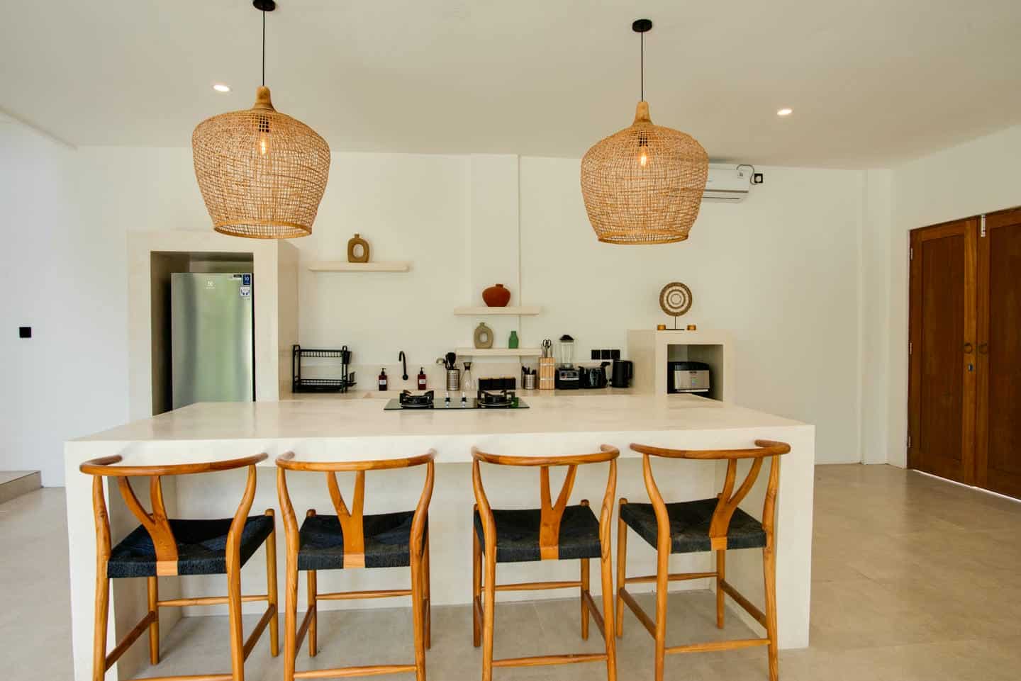 Modern kitchen with wooden chairs and pendant lights.