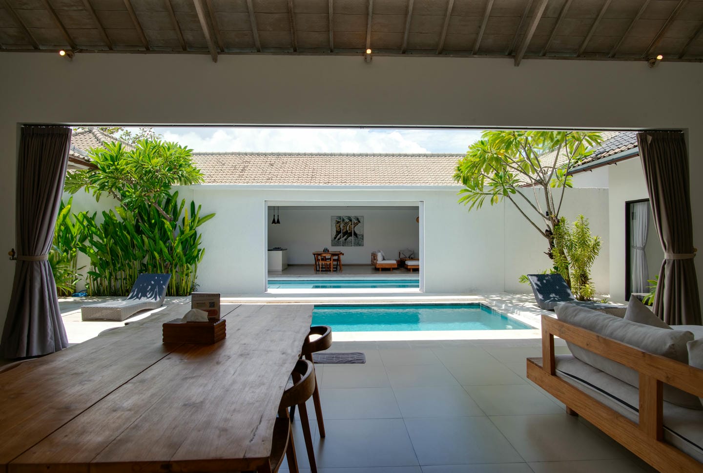 Modern open-air living room with pool view.