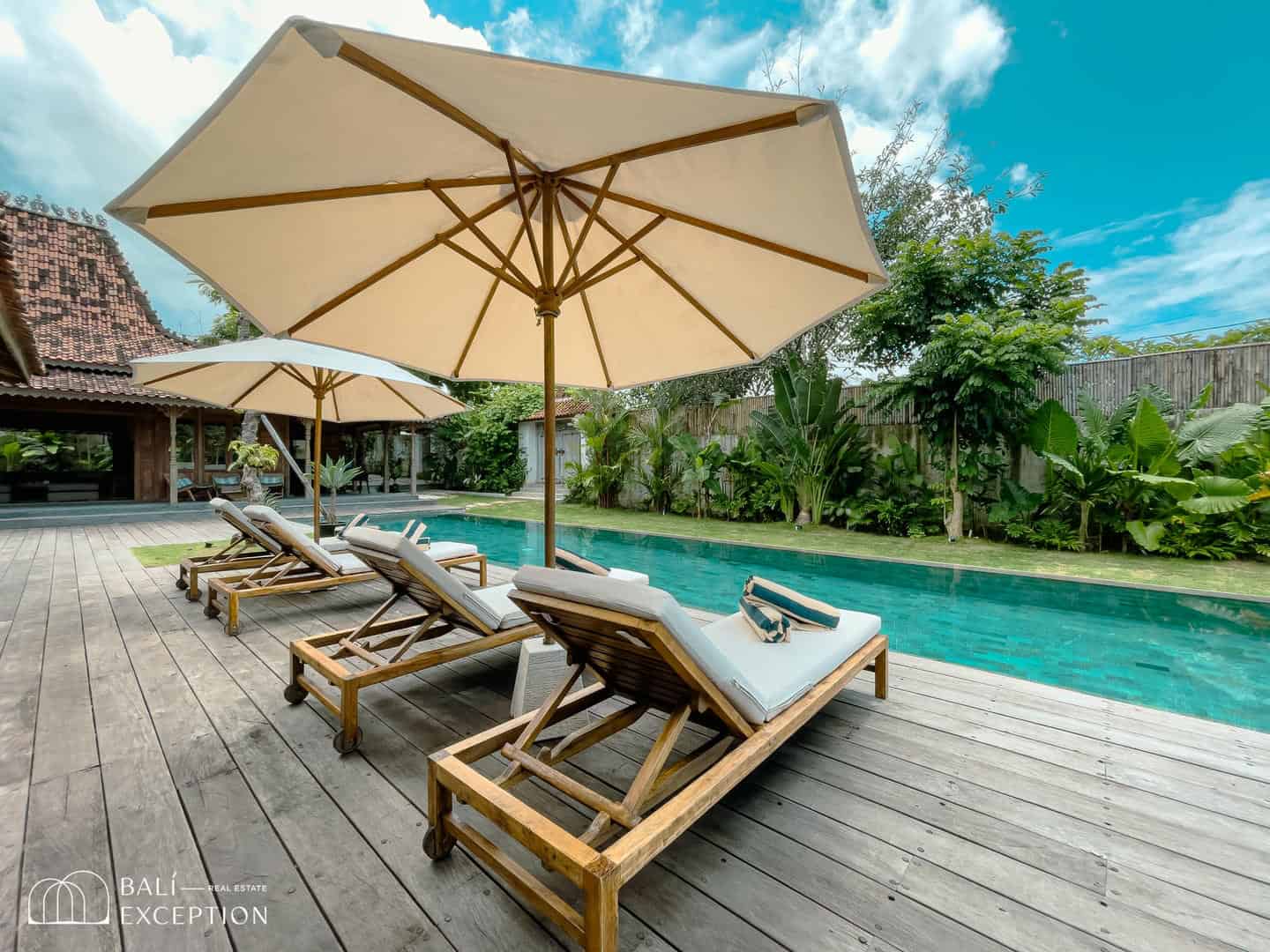 Poolside loungers with umbrellas in tropical setting.