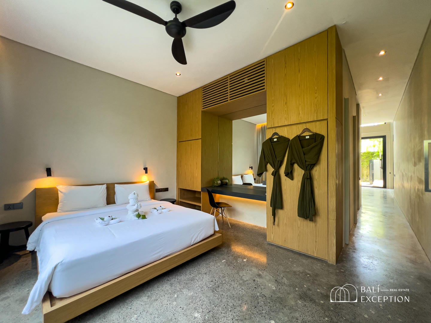 Modern hotel room with double bed and robes.