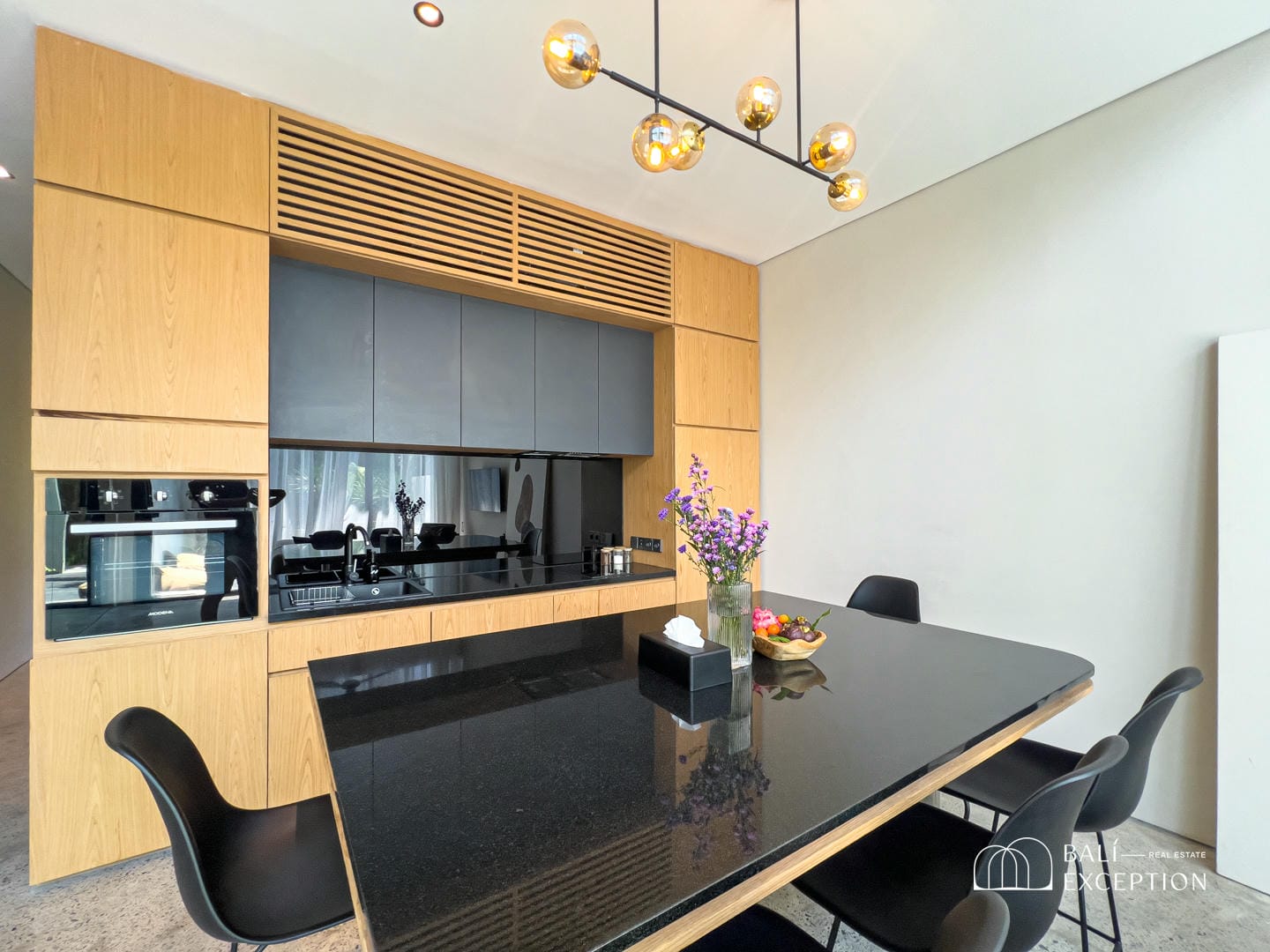 Modern kitchen with black countertop and dining area.