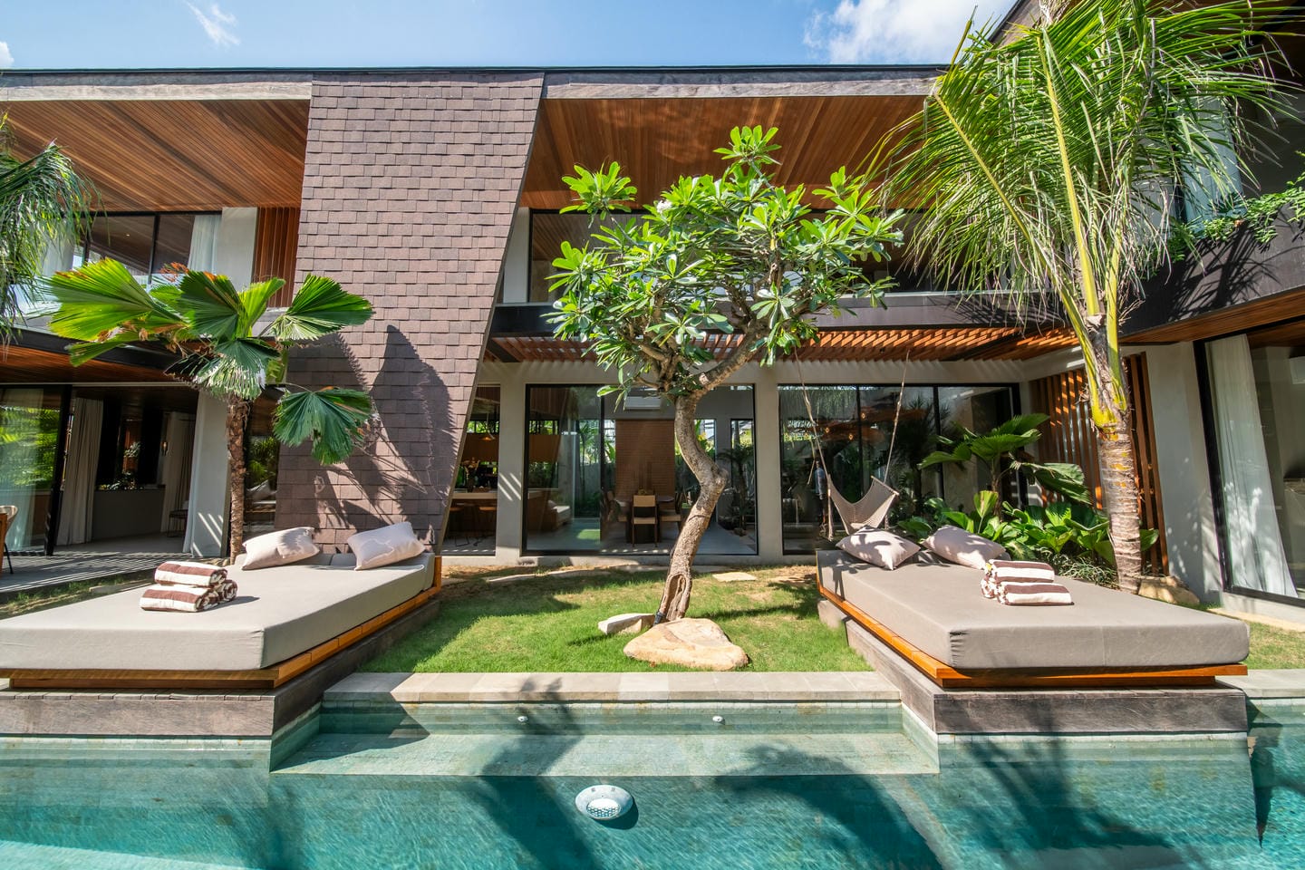 Modern villa garden with pool and loungers.