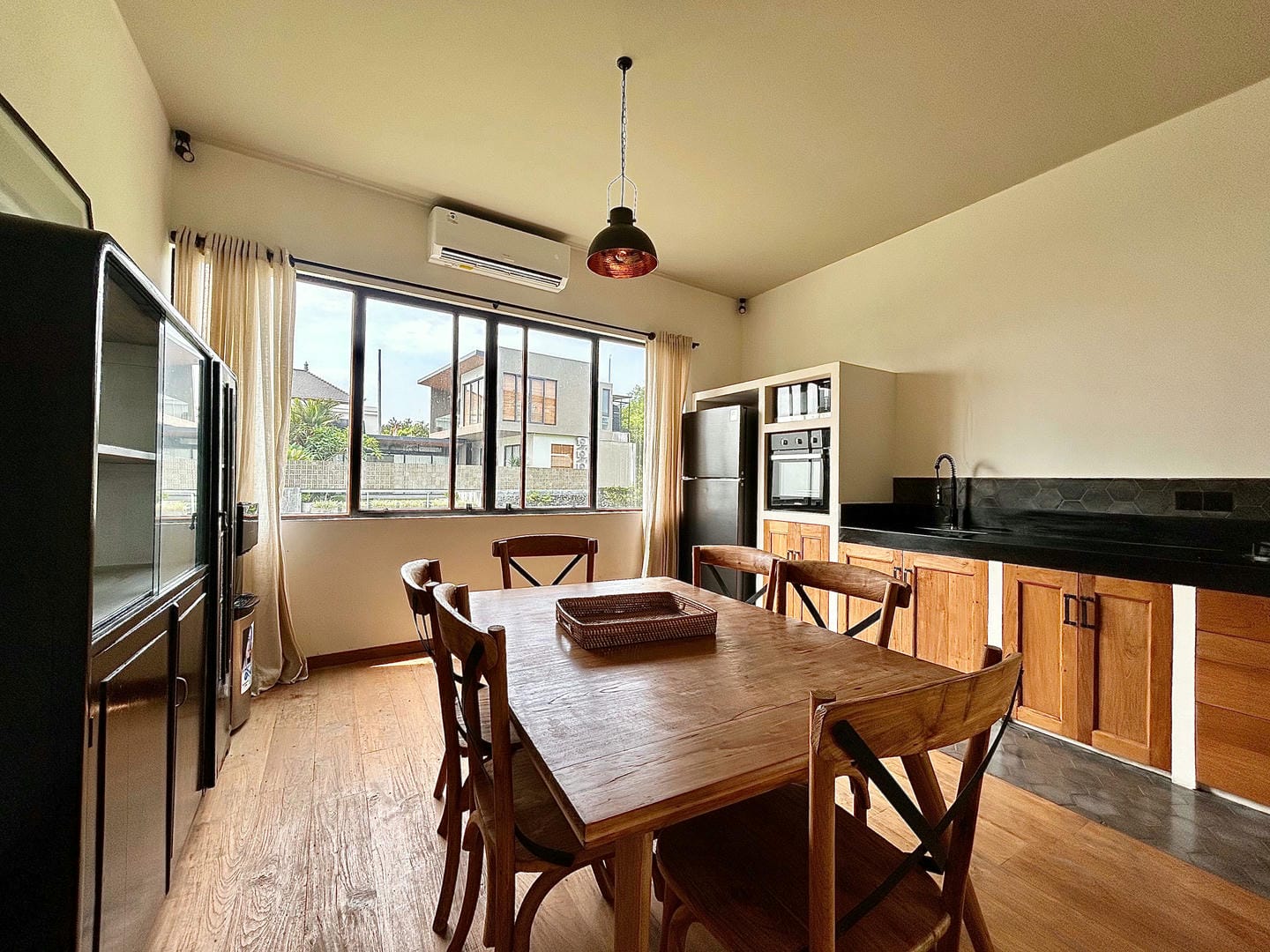 Modern kitchen with wooden table and black countertop.