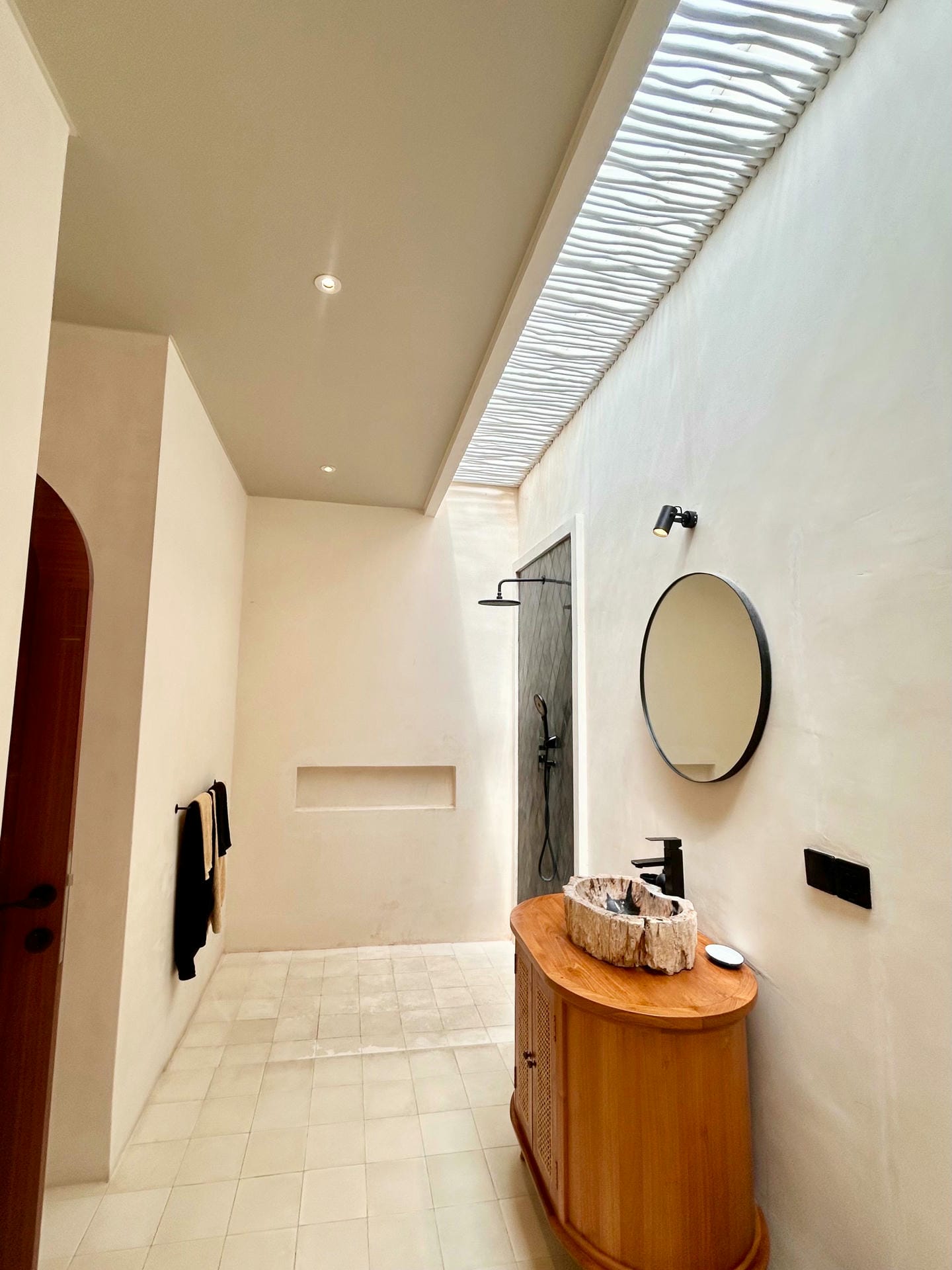 Minimalist bathroom with wooden vanity and skylight.