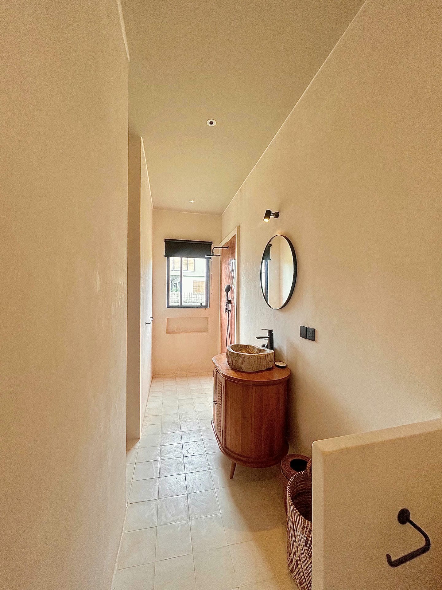 Minimalist bathroom with round mirror and wooden vanity.