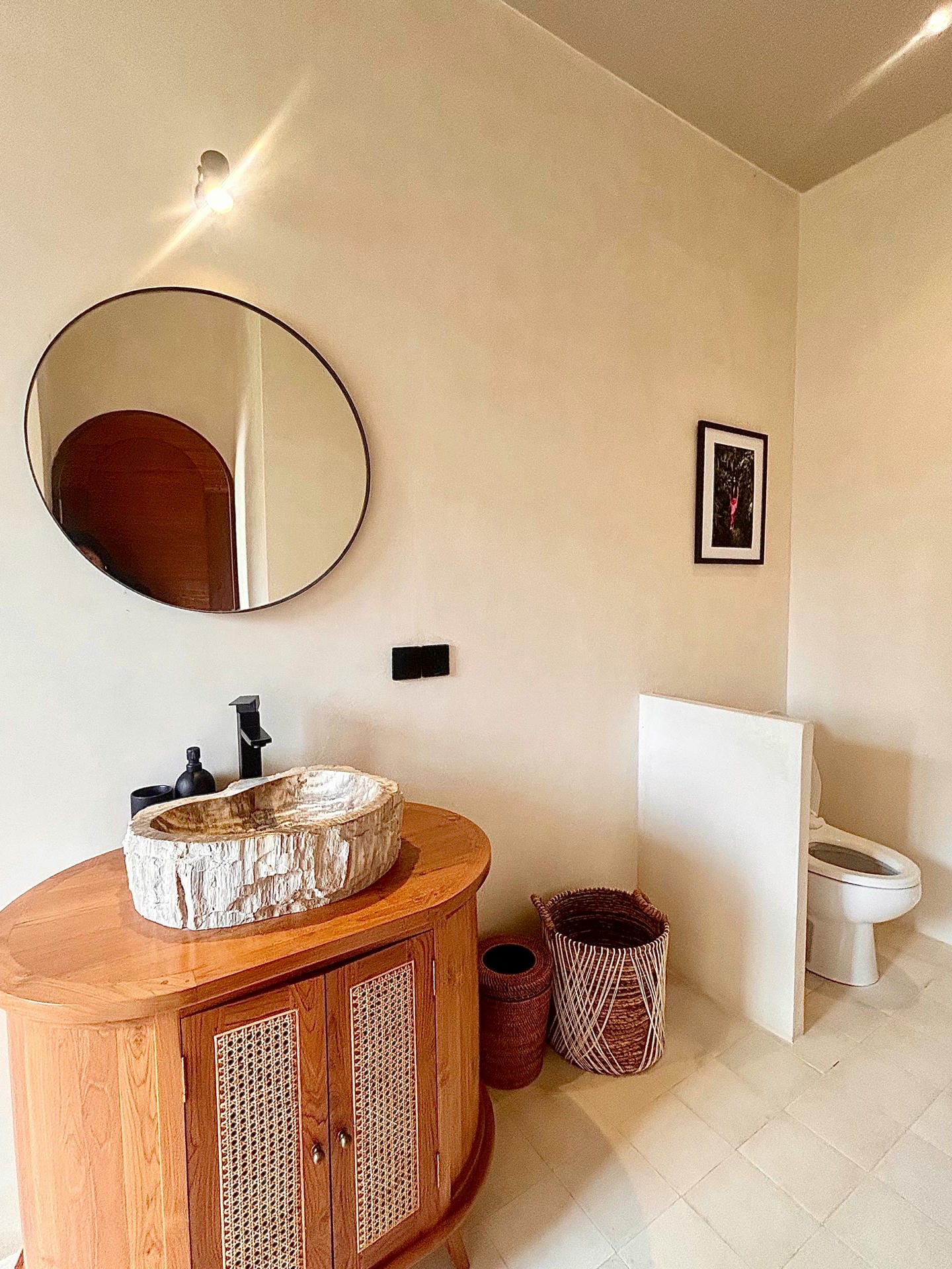 Rustic bathroom with round mirror and wooden vanity.