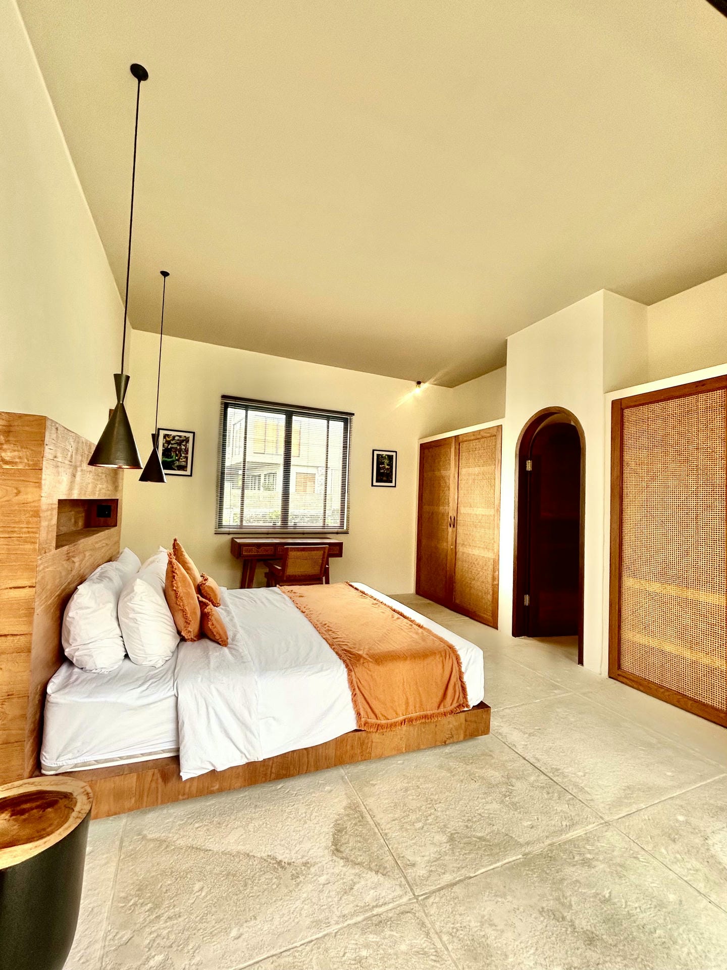 Minimalist bedroom with wooden accents and orange decor.
